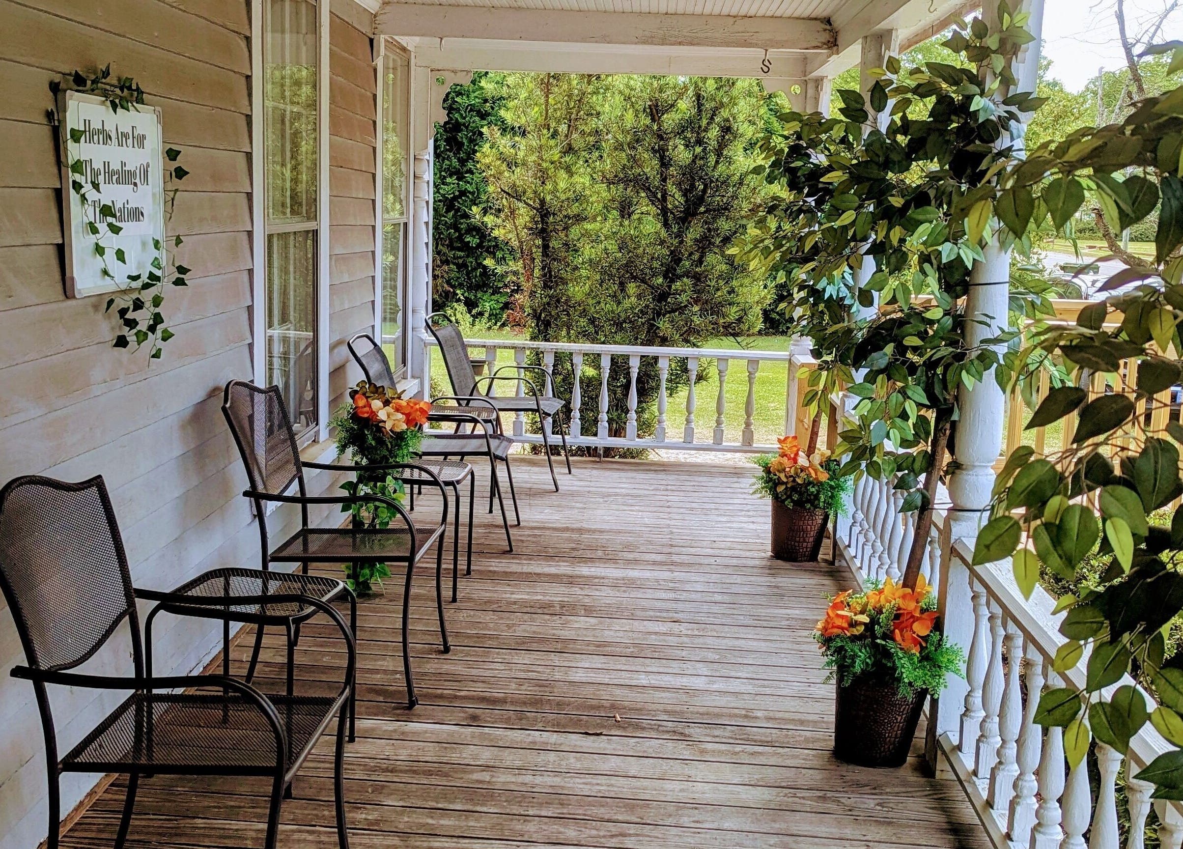 Charming porch at Arlana Styles Manextensions (ASME) in Latta, South Carolina, US, adorned with chairs and lush greenery.