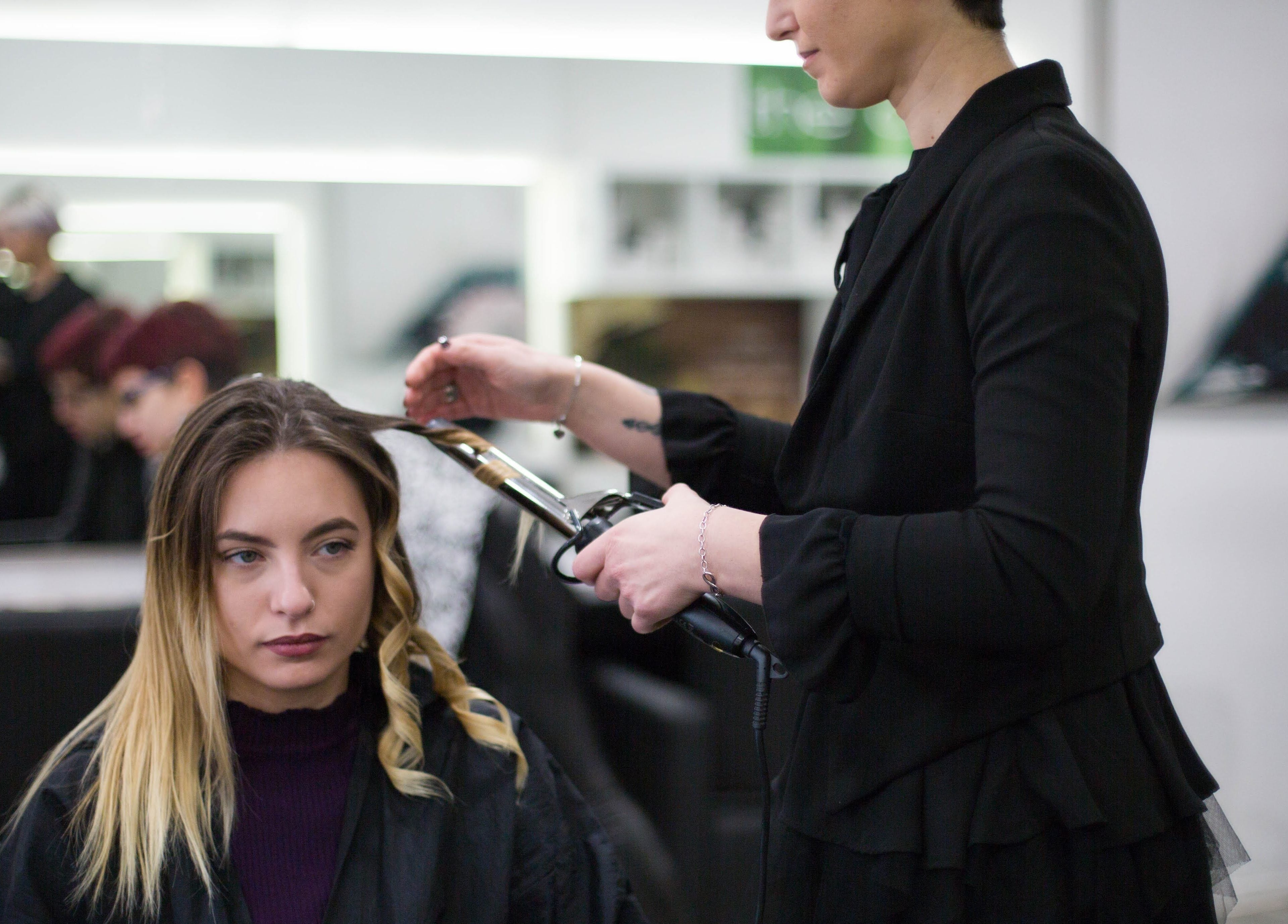 Stylist arriccia i capelli di una cliente presso Elegance Parrucchieri, Pescara, Italia, IT.