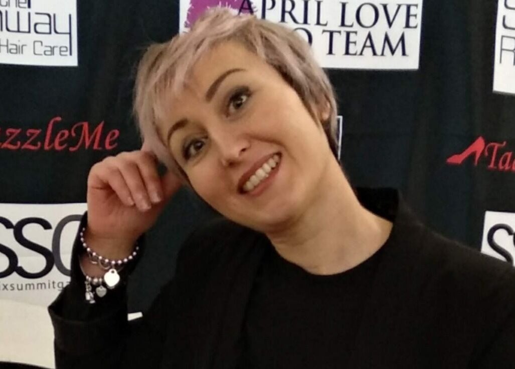 Figurante sorridente a Elegance Parrucchieri, Pescara, Italia, IT, con sfondo di marchi del settore moda.