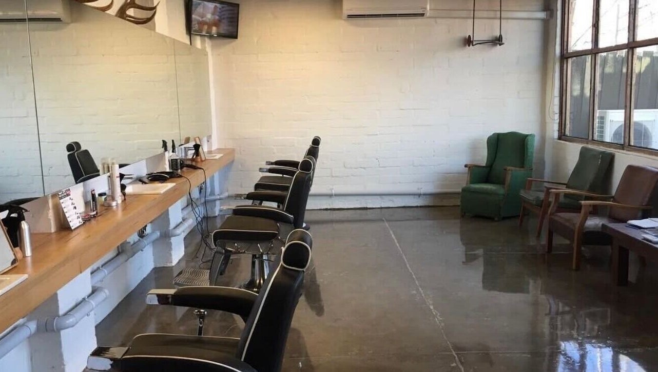 Modern interior of Roy's Barber in Melbourne, Victoria, AU with stylish black chairs and sleek mirrors.