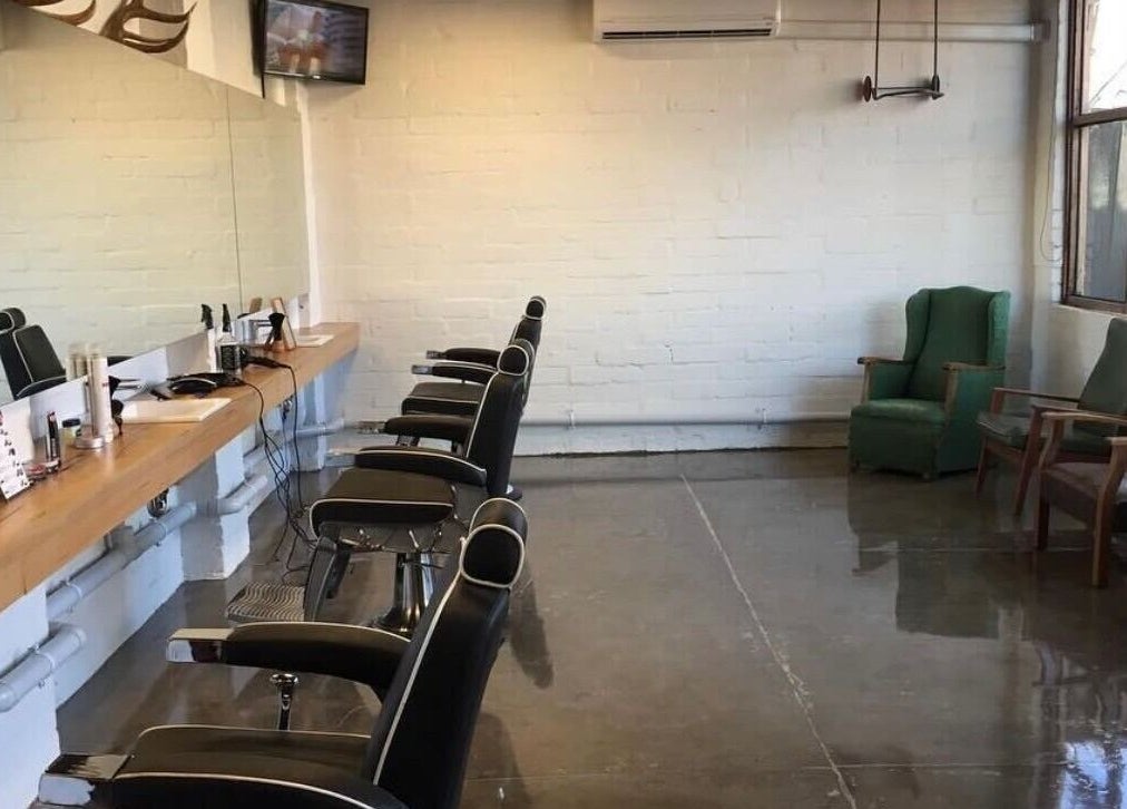 Modern interior of Roy's Barber in Melbourne, Victoria, AU with stylish black chairs and sleek mirrors.