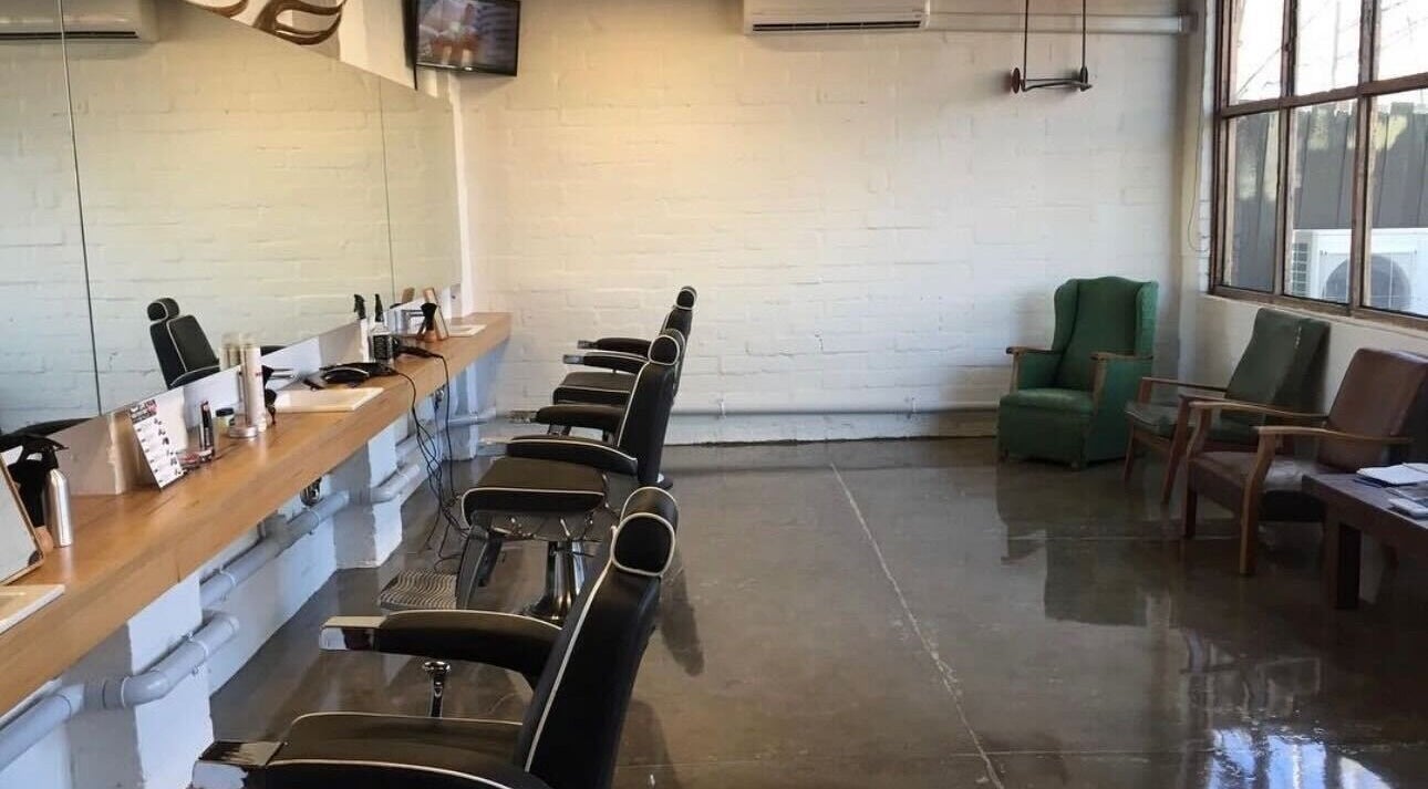 Modern interior of Roy's Barber in Melbourne, Victoria, AU with stylish black chairs and sleek mirrors.