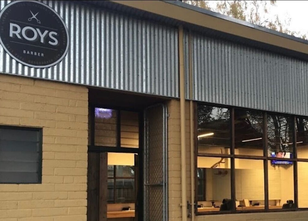 Exterior view of Roy's Barber in Melbourne, Victoria, AU, featuring a rustic brick and metal design.