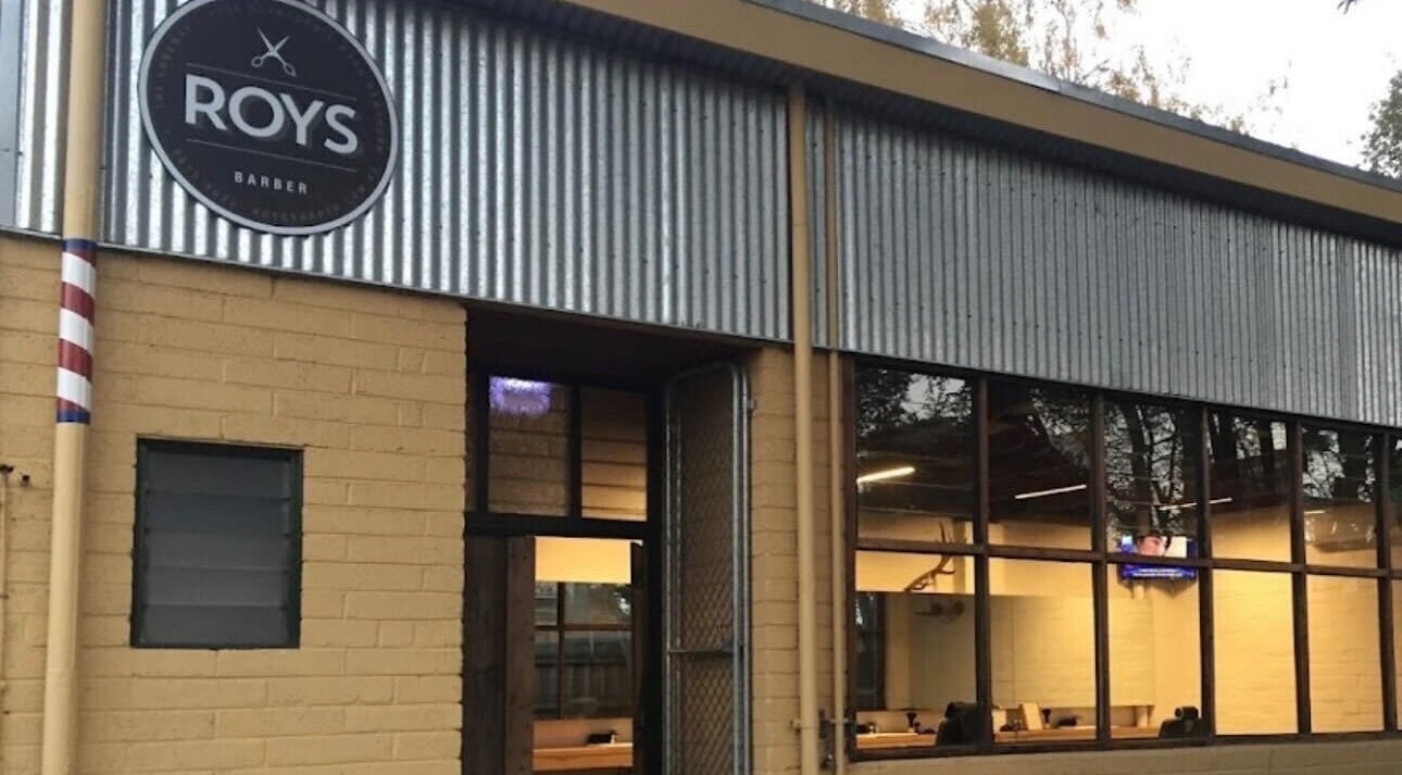 Exterior view of Roy's Barber in Melbourne, Victoria, AU, featuring a rustic brick and metal design.