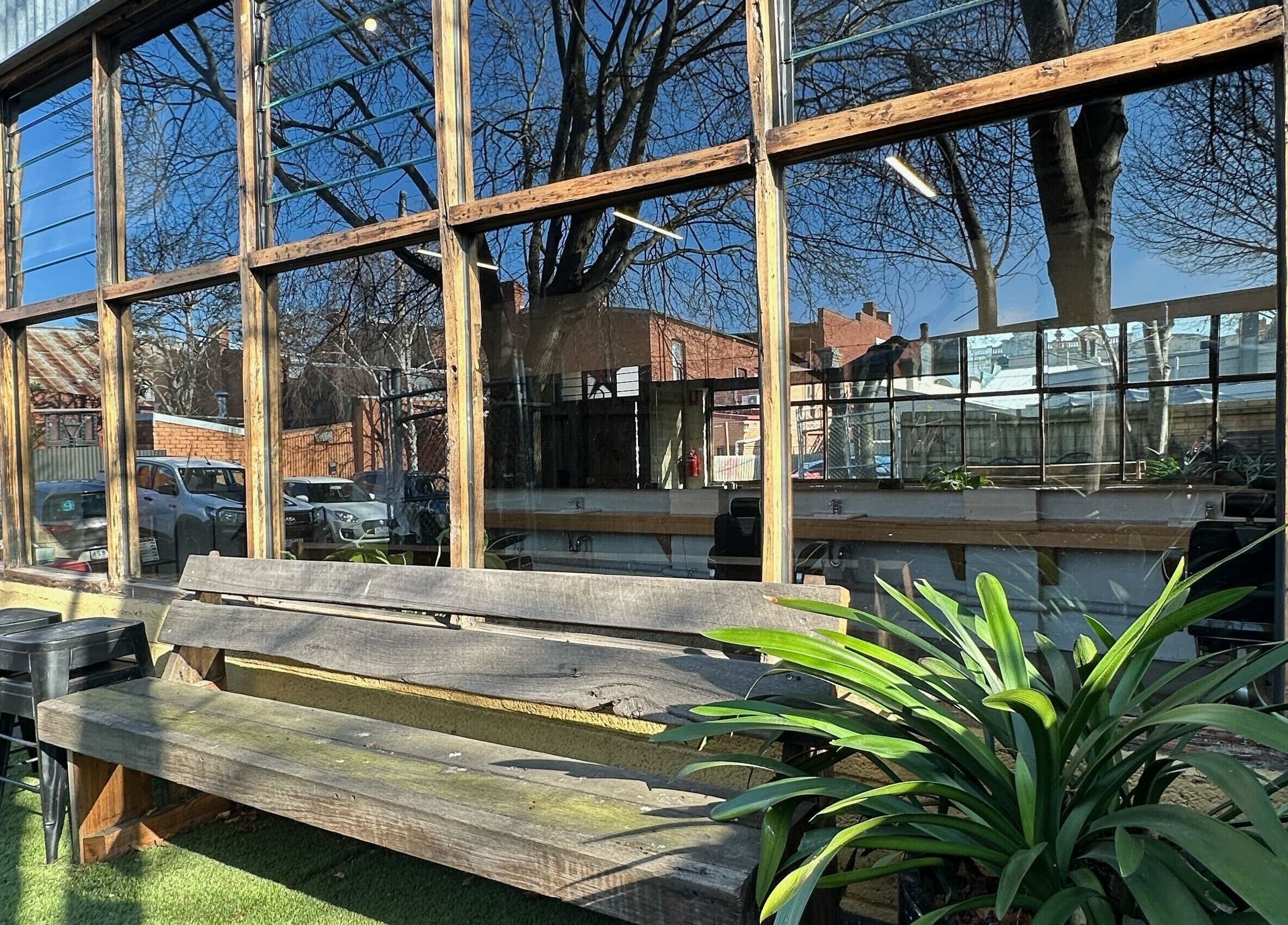 Exterior view of Roy's Barber in Melbourne, Victoria. Rustic benches and plants accentuate the charming atmosphere.