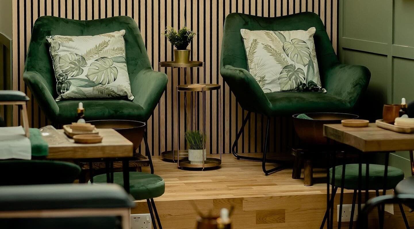 Elegant seating at Arabella Beauty in Hitchin, England, GB, showcasing plush green chairs and wooden decor.