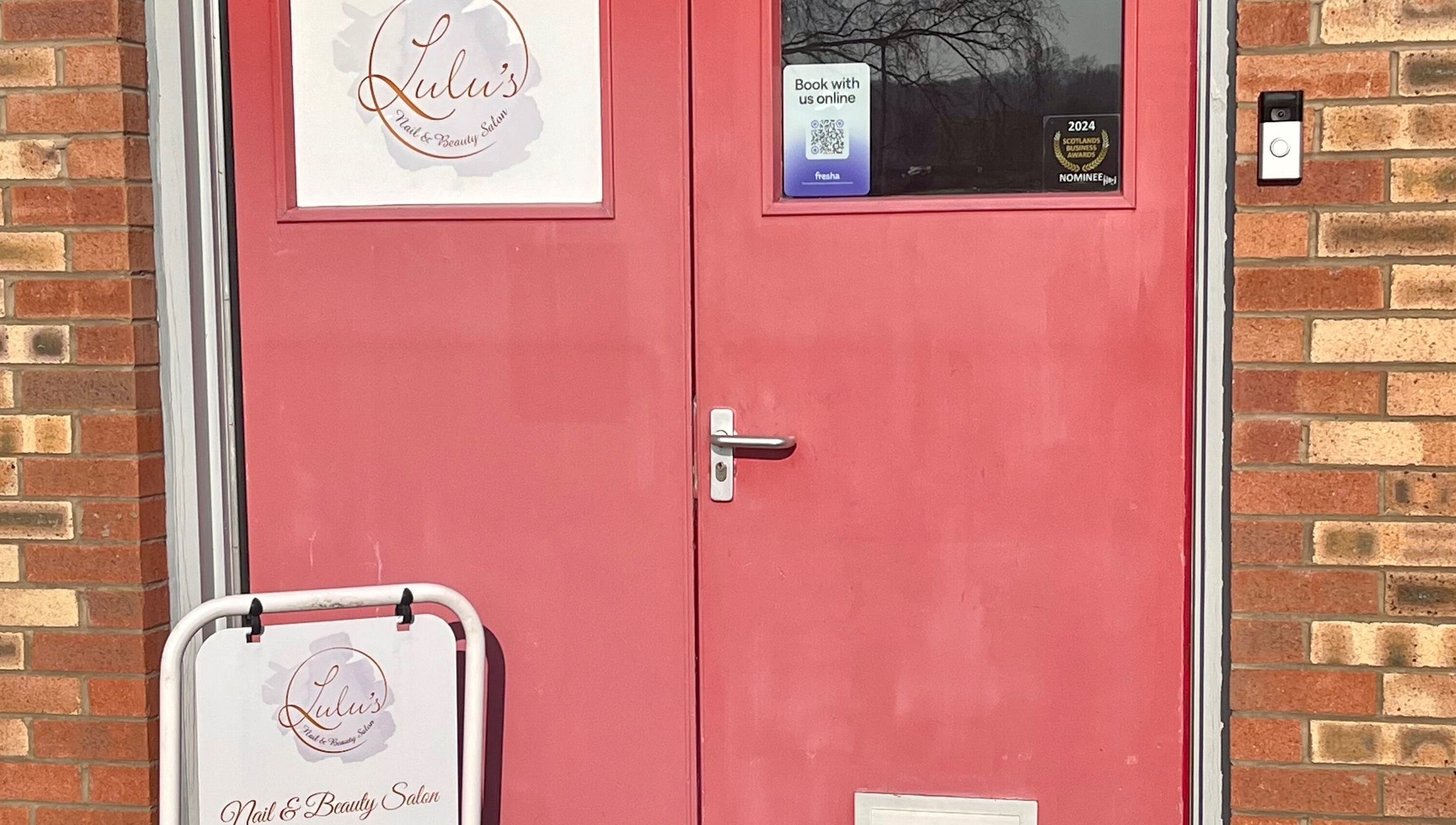 Red door entrance to LS Beauty and Massage in Linlithgow, Scotland, GB, with salon signage.