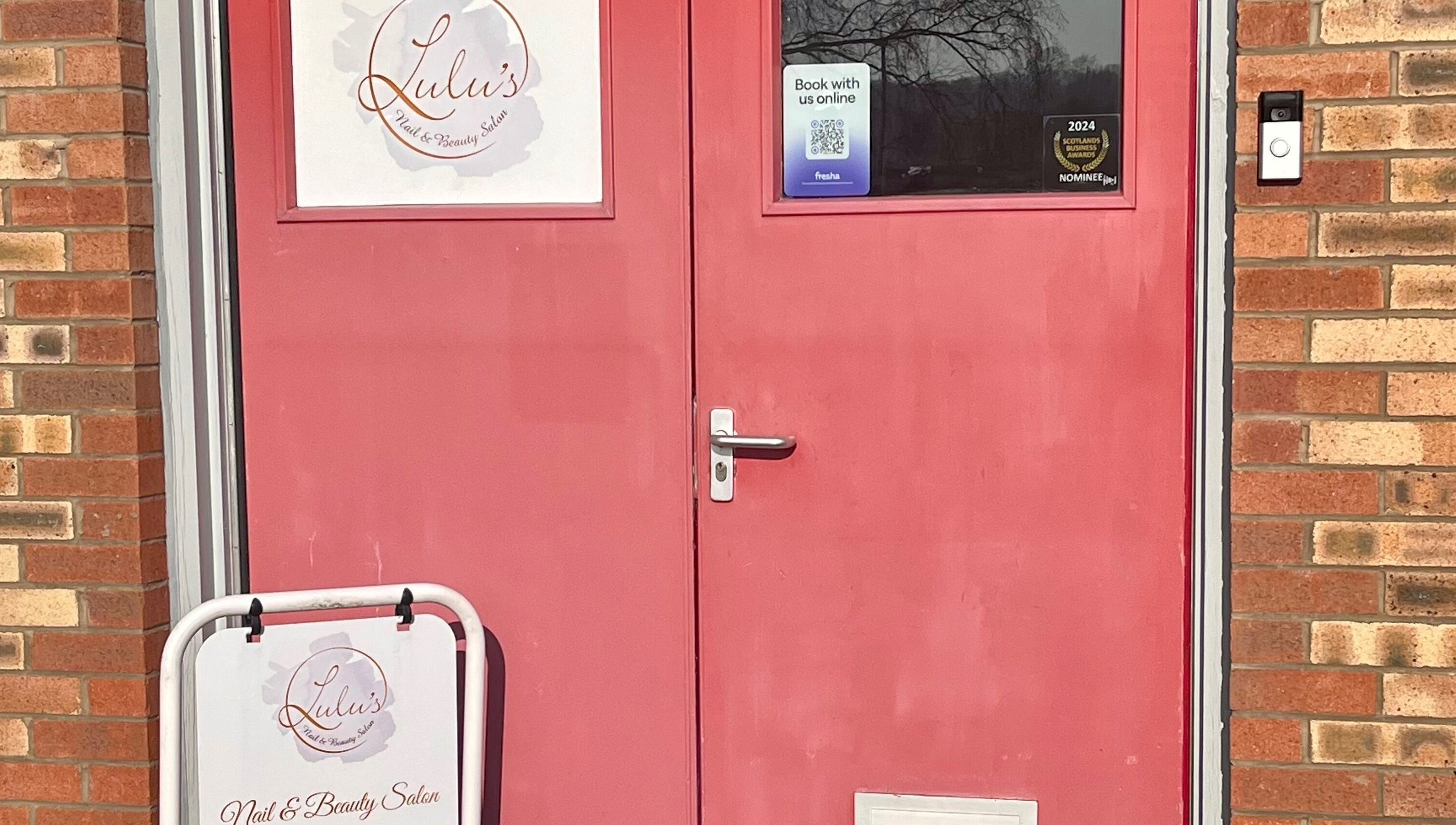 Red door entrance to LS Beauty and Massage in Linlithgow, Scotland, GB, with salon signage.