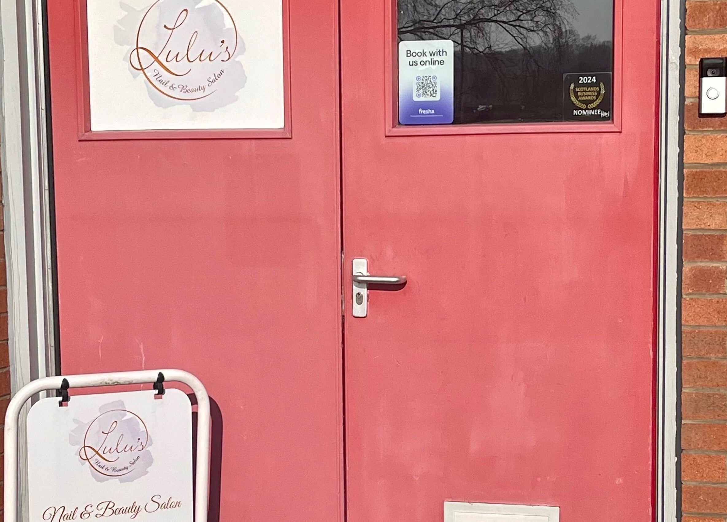 Red door entrance to LS Beauty and Massage in Linlithgow, Scotland, GB, with salon signage.