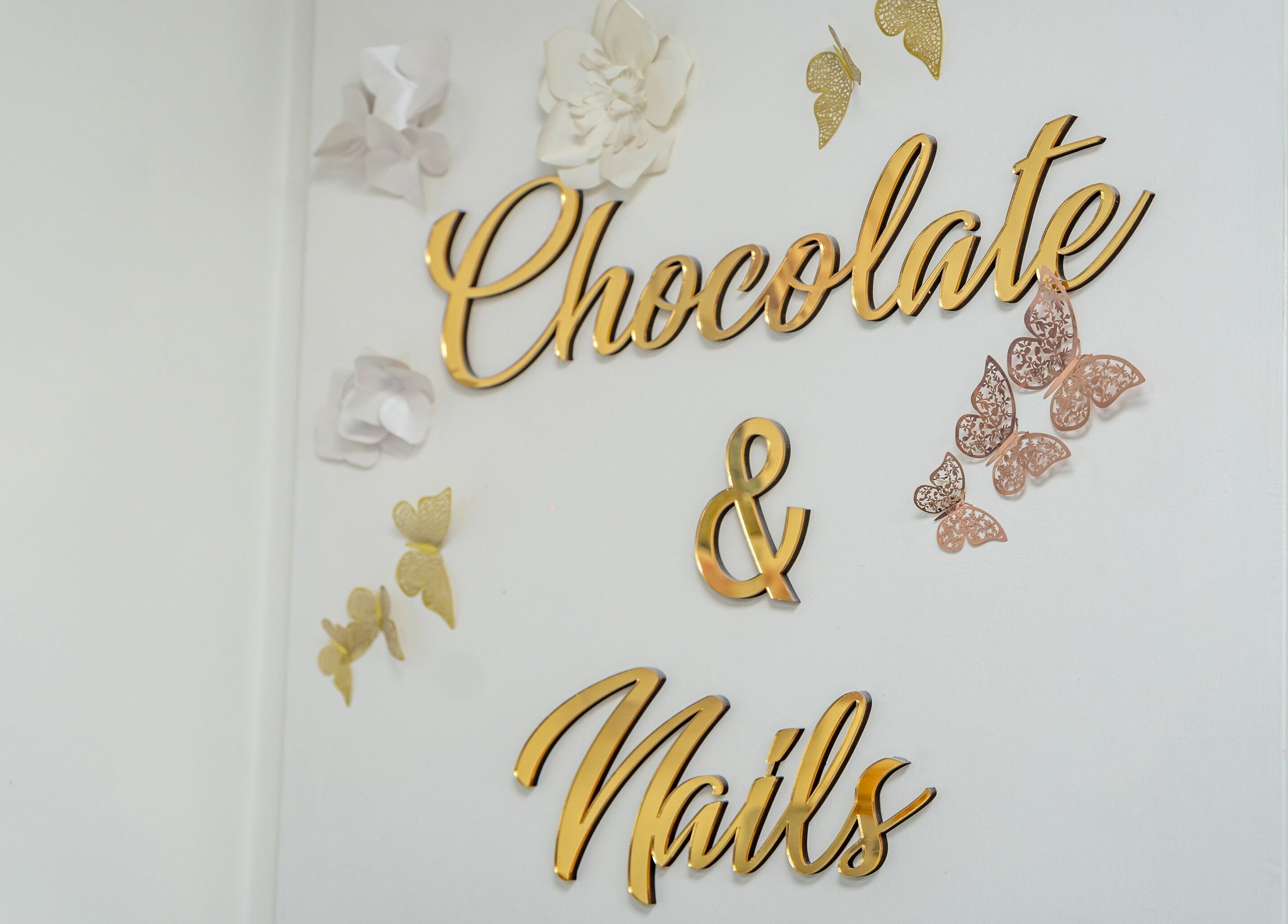 Elegant signage of Chocolate & Nails - Ealing Broadway, London, England, GB with gold lettering and art.