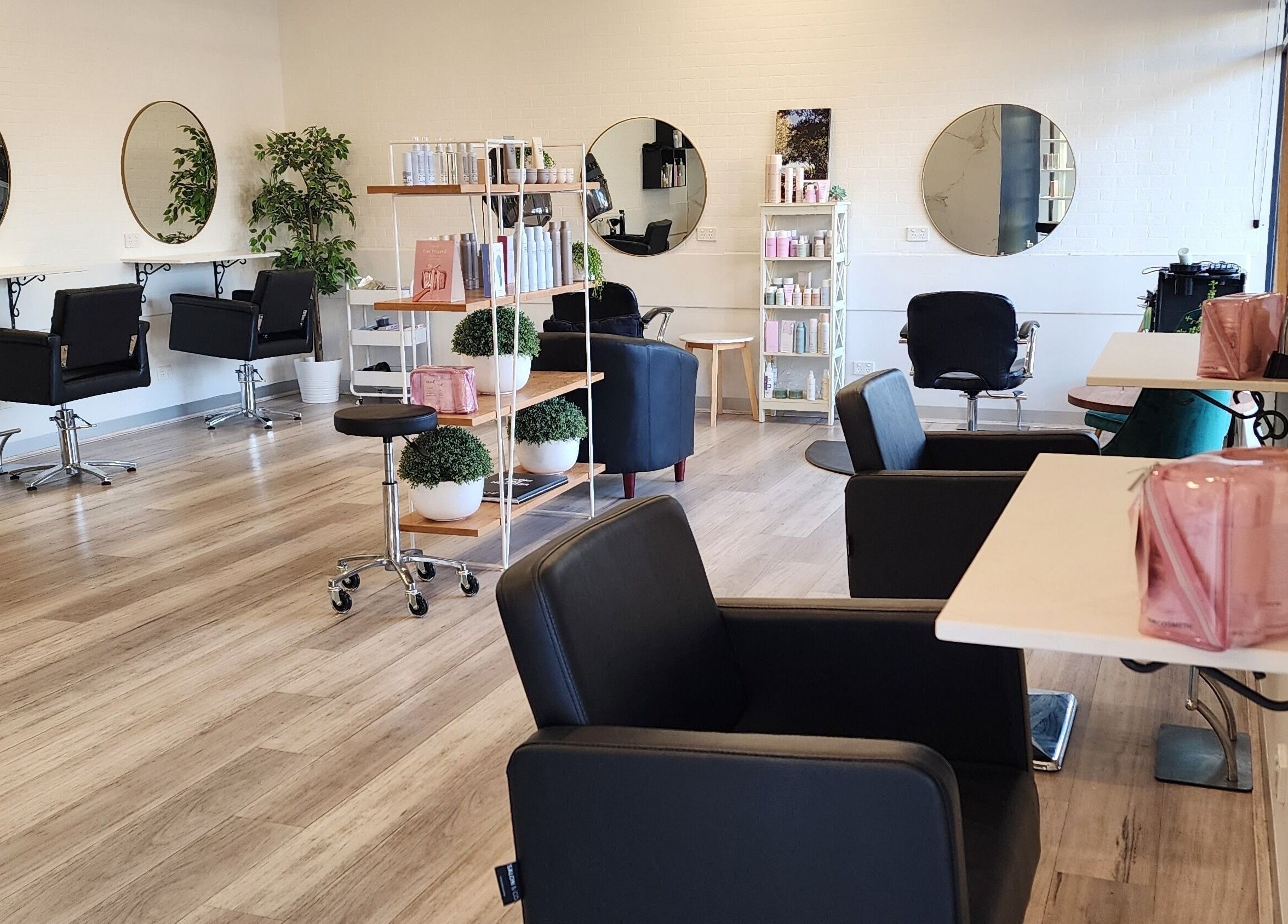 Chic interior of Hair In Bittern, Bittern, Victoria, AU, featuring stylish salon chairs and large round mirrors.