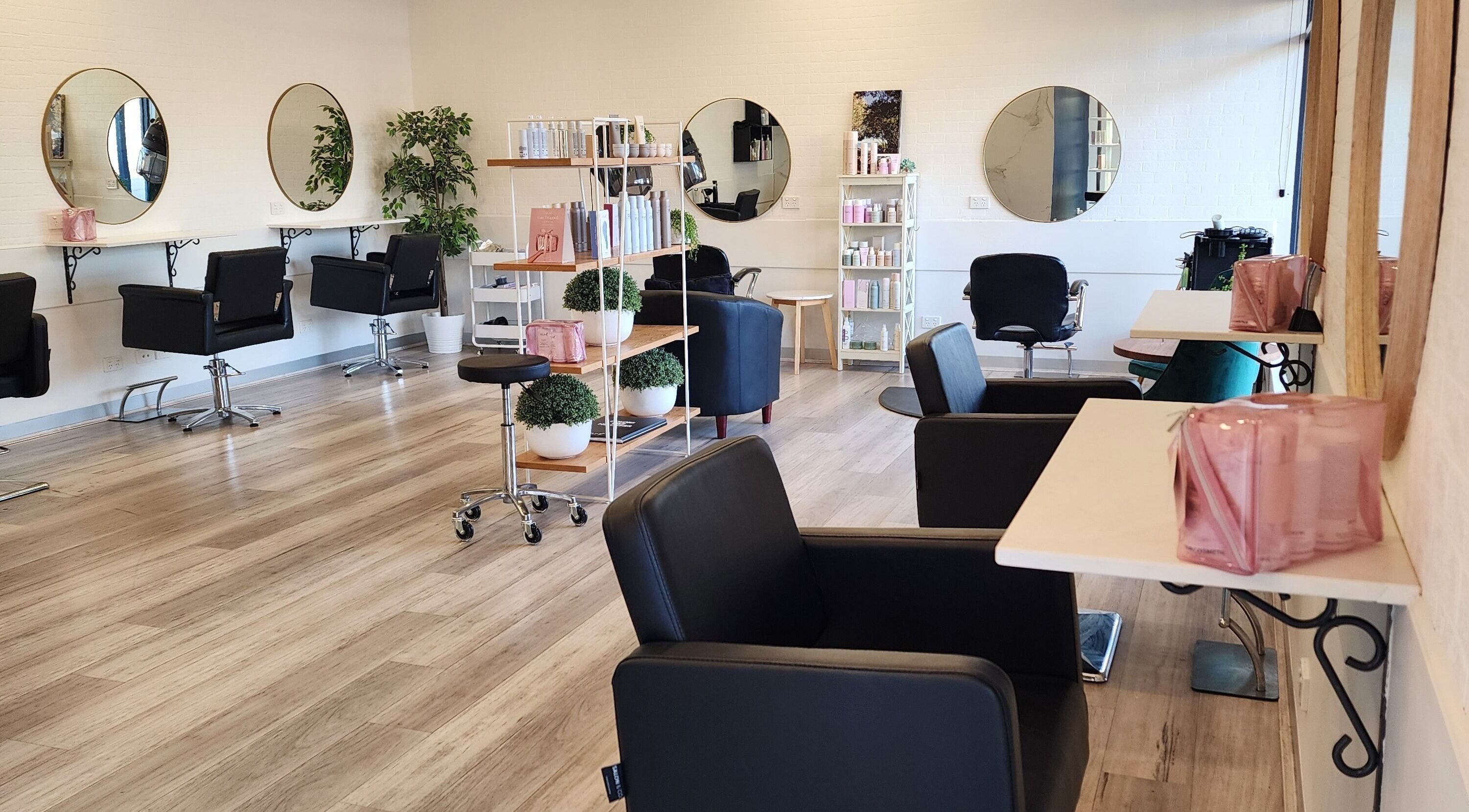 Chic interior of Hair In Bittern, Bittern, Victoria, AU, featuring stylish salon chairs and large round mirrors.