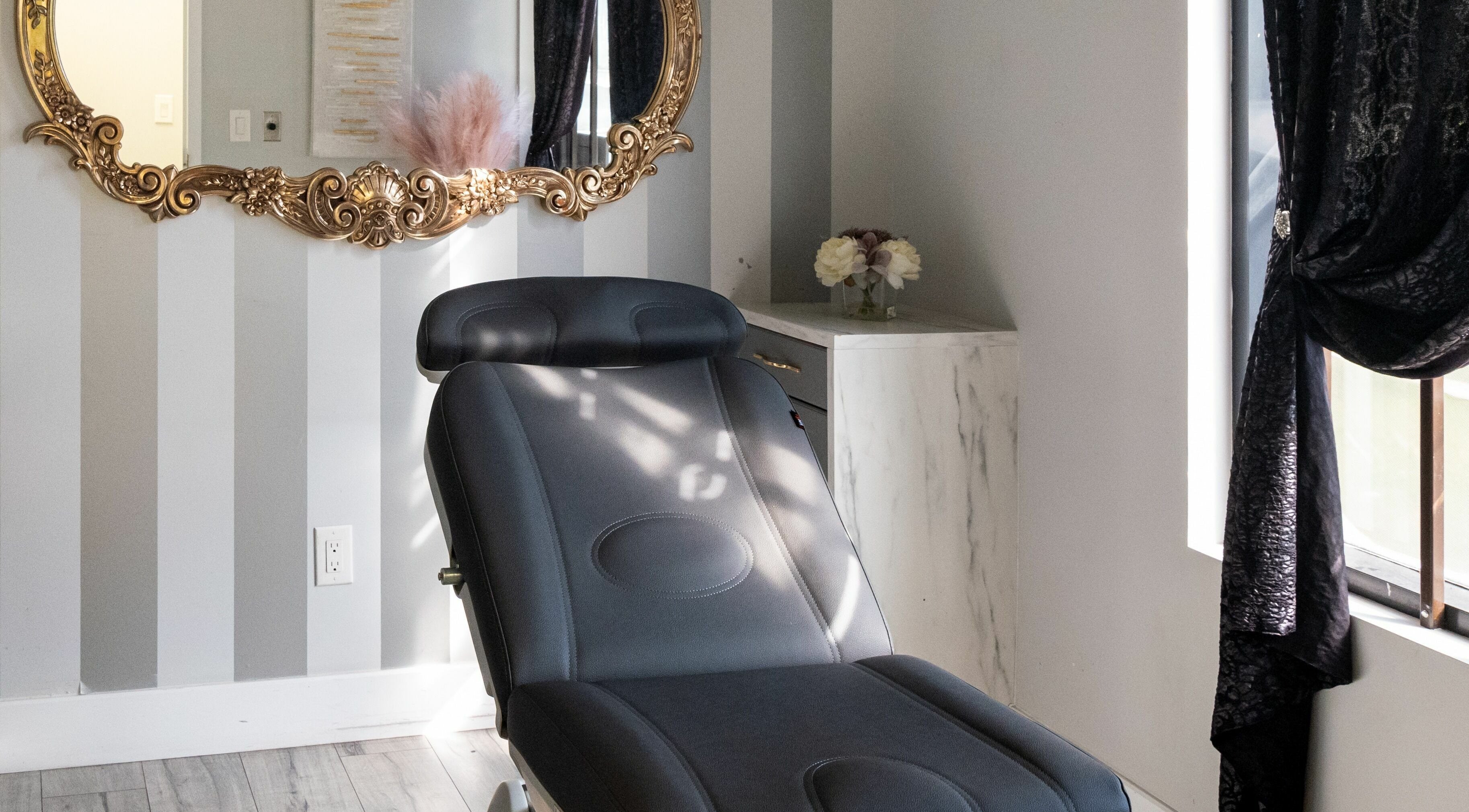 Elegant treatment room at Elysian Beauty Bar Inc, Windsor, Ontario, CA with a chic chair and ornate mirror.