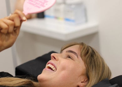 Client smiling at Beauty at Caitlyn’s in Harrington Park, New South Wales, AU, admiring beauty treatment results.