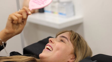 Client smiling at Beauty at Caitlyn’s in Harrington Park, New South Wales, AU, admiring beauty treatment results.