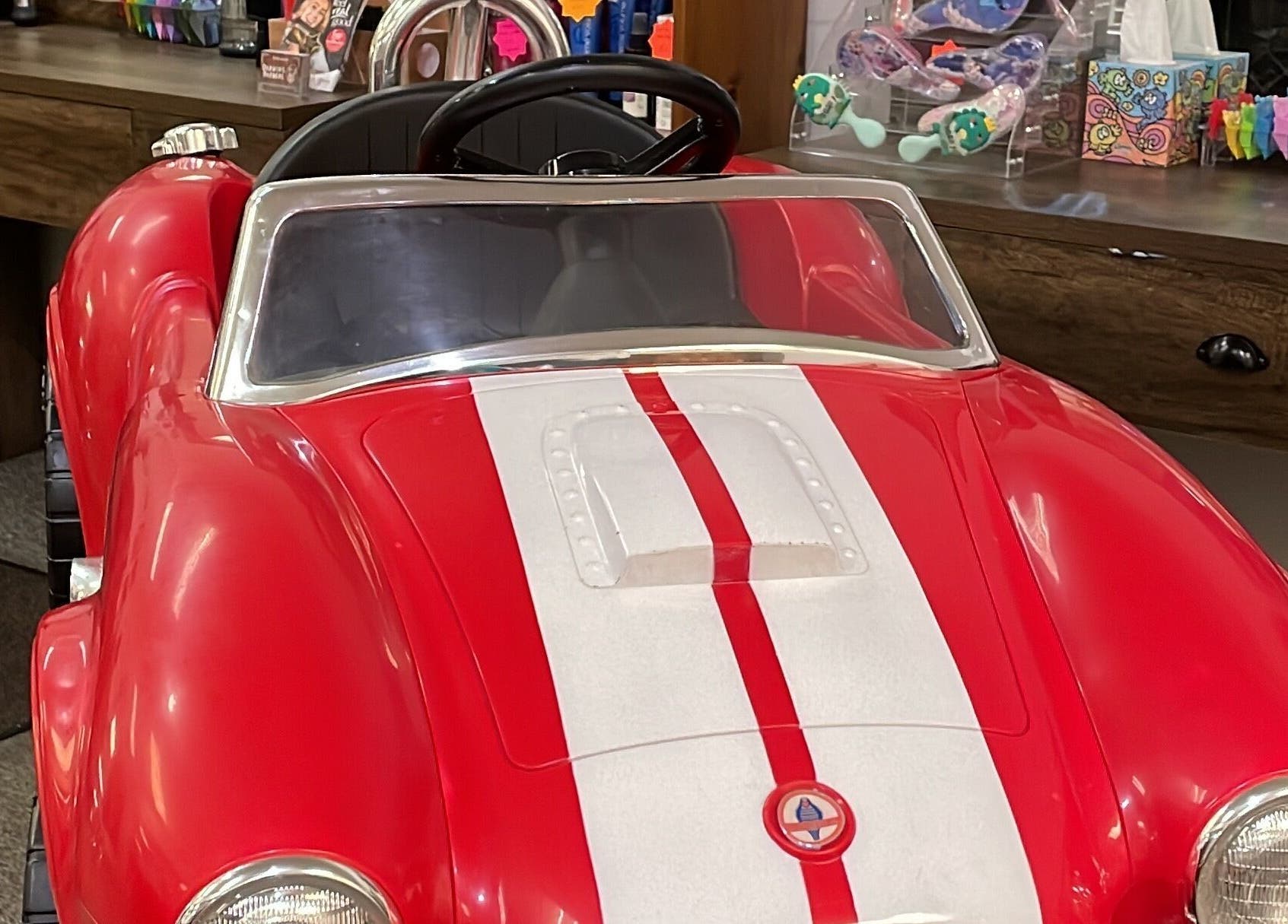 Red children's car chair in Darwin's Barbers, Shrewsbury, England, GB, creating a fun, engaging haircut experience.