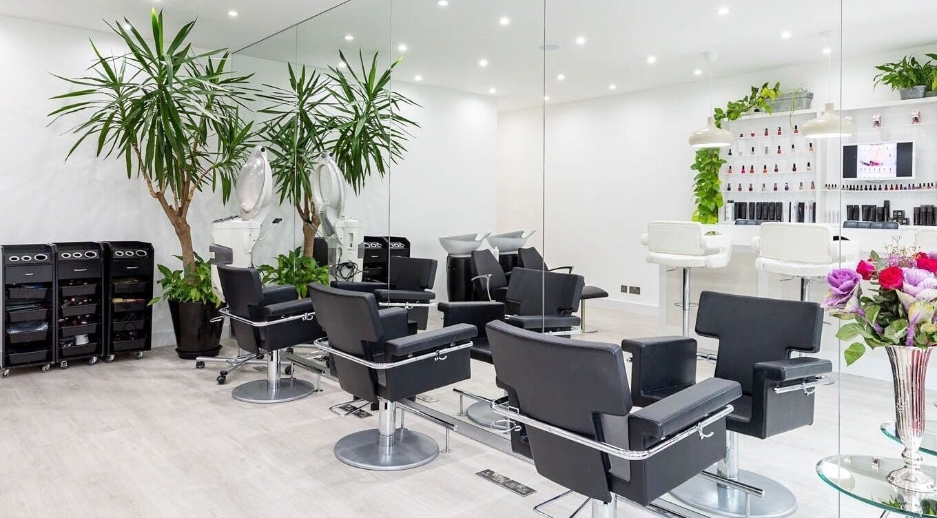 Modern interior of Athena Salons Hair & Nails in London, England, GB, featuring sleek chairs and vibrant plants.