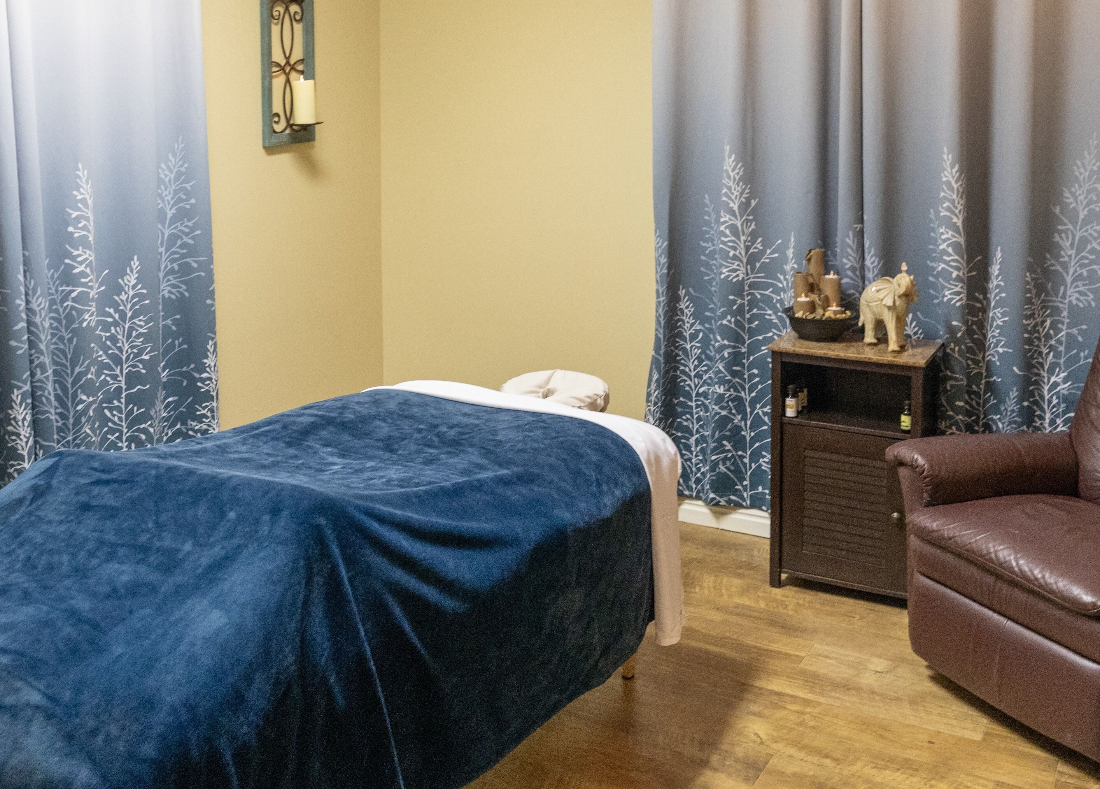Cozy massage room at Return To Harmony in Draper, Utah, US with soft blue decor and calming ambiance.