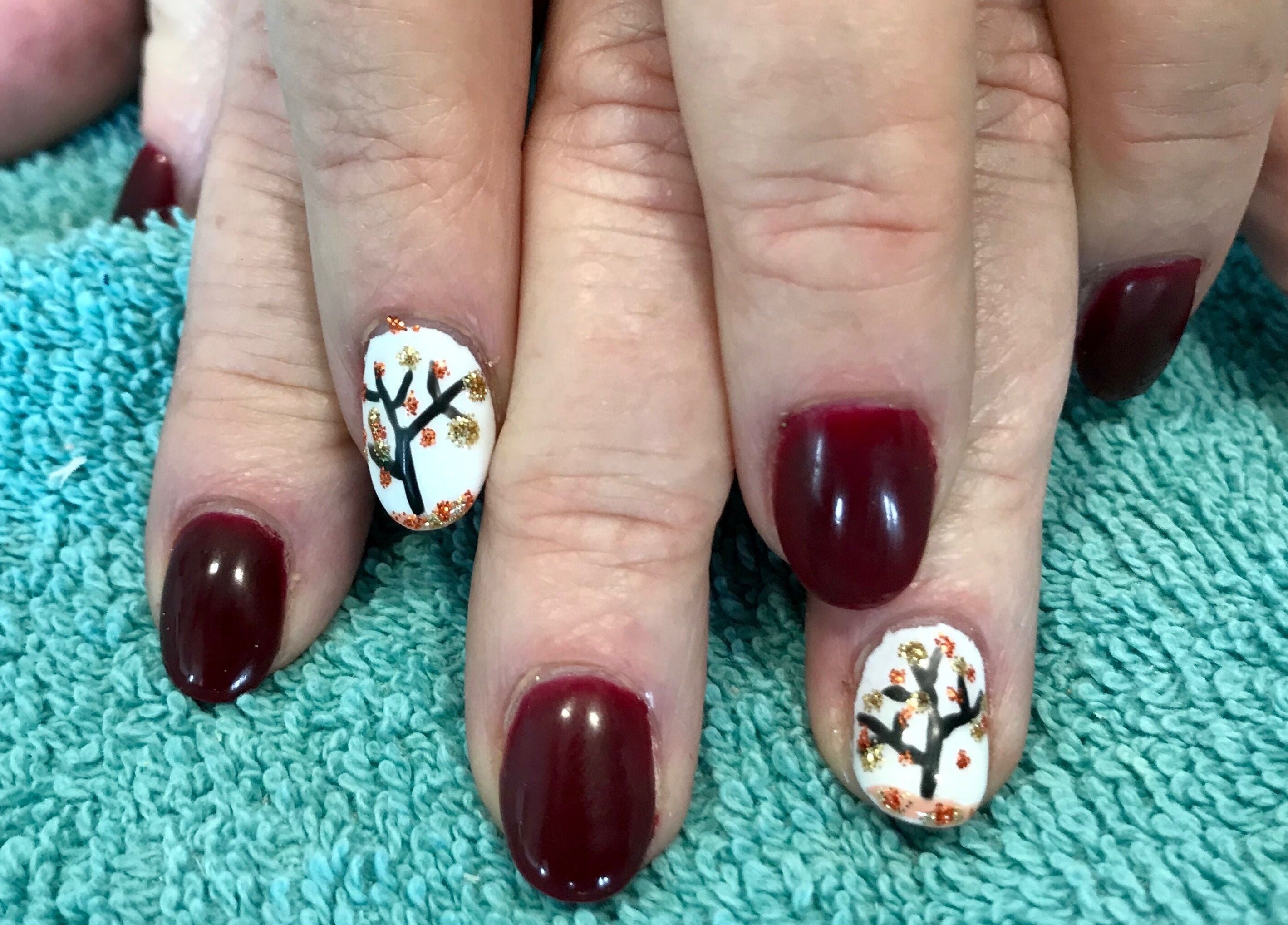 Elegant autumn-themed nail art at Head to Toe Studio, Arvada, Colorado, US on a soft blue towel.