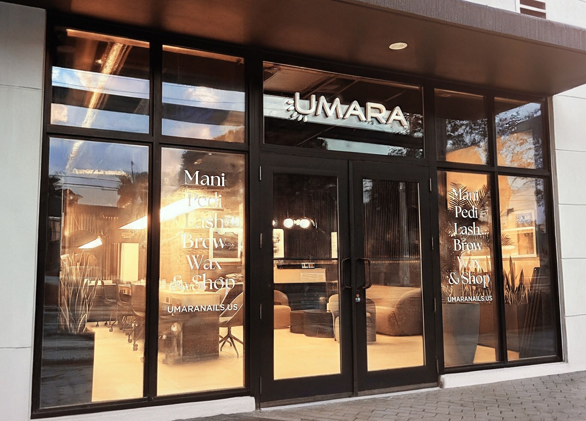 Entrance of UMARA beauty venue in Miami, Florida, US featuring modern glass doors and a warm interior glow.