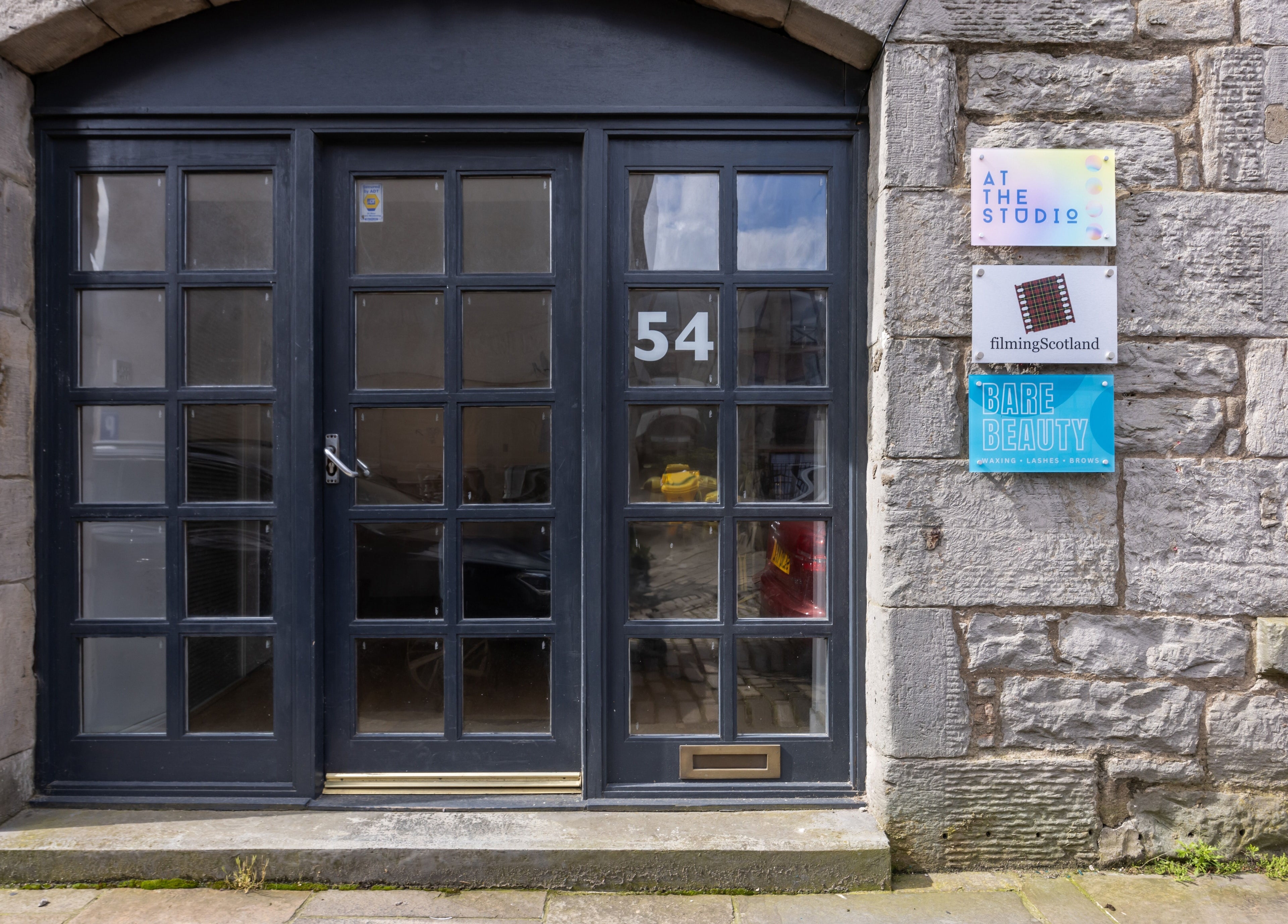 Entrance of Bare Beauty in Edinburgh, Scotland, GB, featuring stylish glass doors and signage.