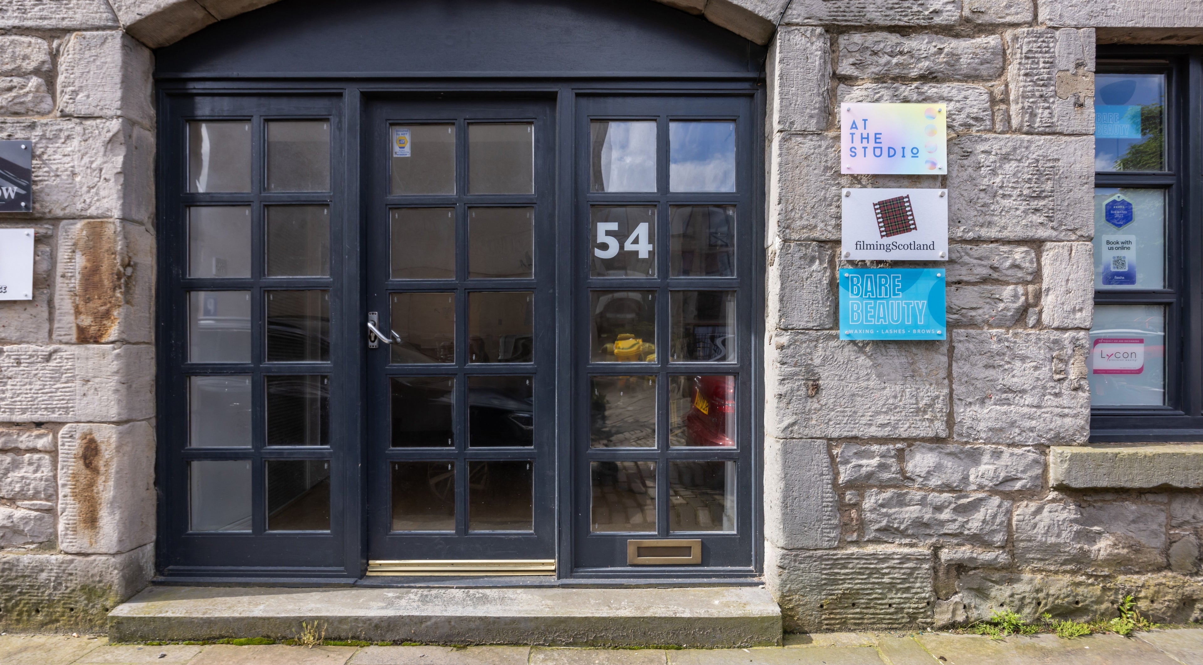 Entrance of Bare Beauty in Edinburgh, Scotland, GB, featuring stylish glass doors and signage.