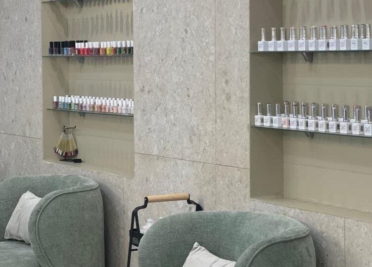 منطقة جلوس مريحة بمقاعد خضراء وأرفف طلاء الأظافر في صالون يونيكوير للسيدات بالخبر.