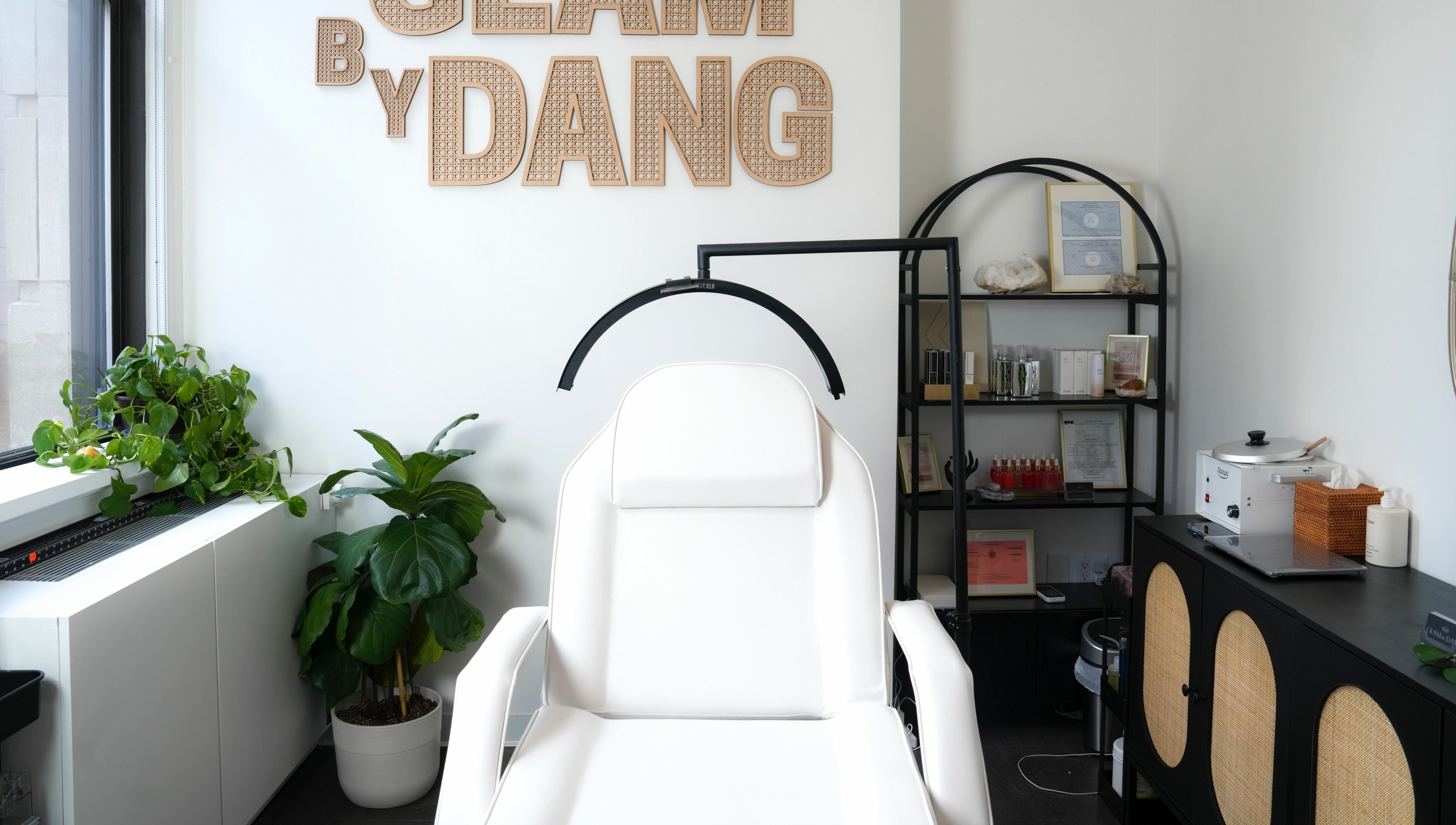 Glam by Dang spa room with a white chair, plants, and shelves in New York, New York, US.
