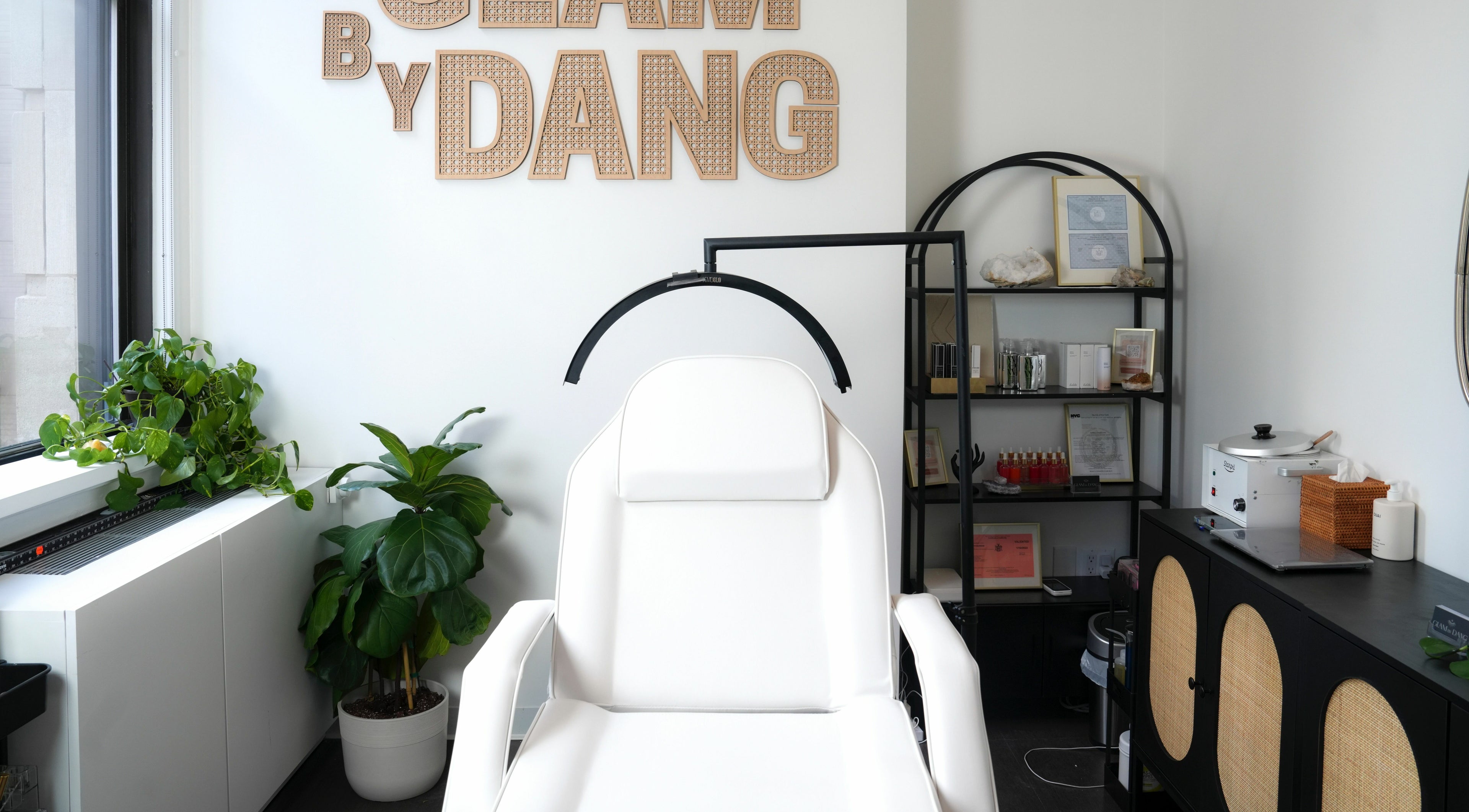 Glam by Dang spa room with a white chair, plants, and shelves in New York, New York, US.