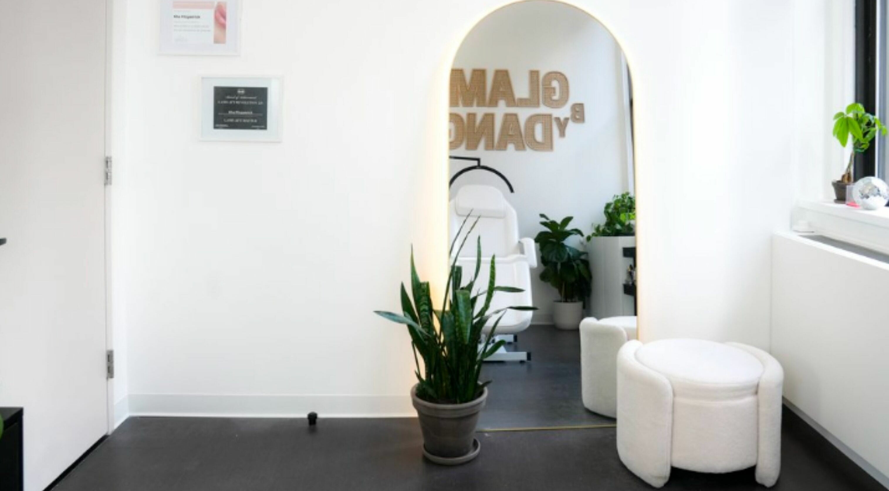 Serene interior at Glam by Dang, New York, New York, US, featuring a chic mirror, stylish seating, and verdant plants.