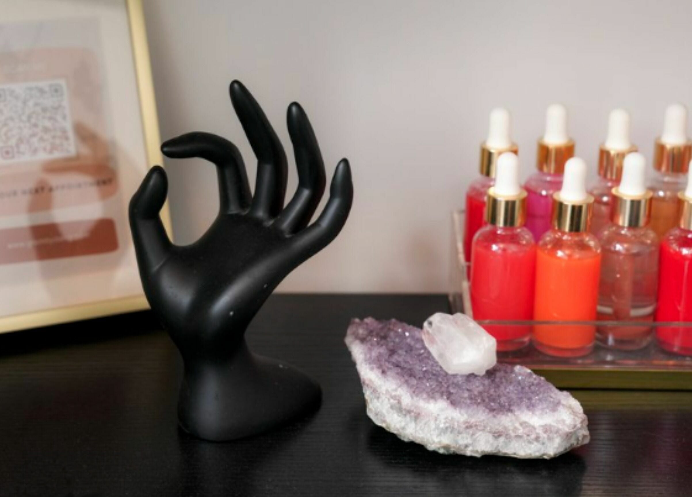 Elegant display at Glam by Dang, New York, New York, US featuring colorful serums, a hand sculpture, and a crystal.