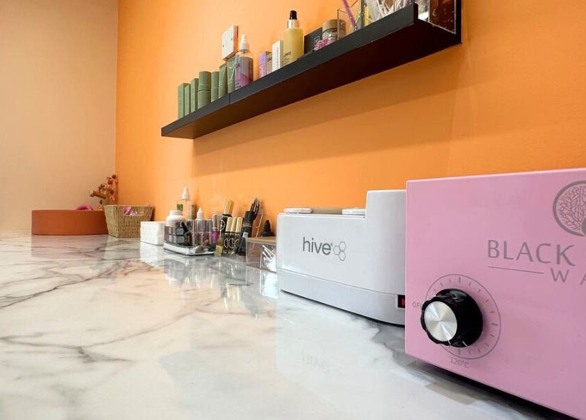 Waxing supplies and equipment at Peach Wax Studio, Kelso, Scotland, GB with vibrant orange wall.