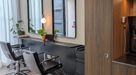 Contemporary styling area at That German Hairdresser, London, England, GB with chairs, mirrors, and plants.