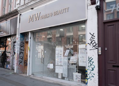 Exterior of MW Nails and Beauty Salon, London, England, GB, showcasing chic glass frontage on a city street.