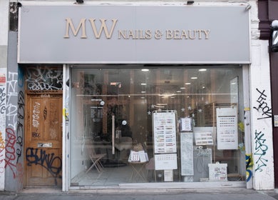 Front of MW Nails and Beauty Salon in London, England. Modern glass facade with beauty service displays.