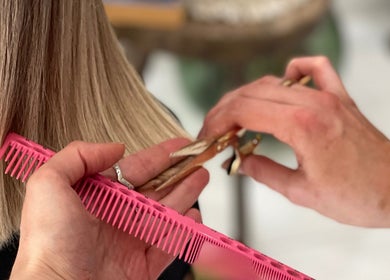 Hair stylist trims blonde hair with scissors at Morgelyn Studio, Penzance, England, GB.