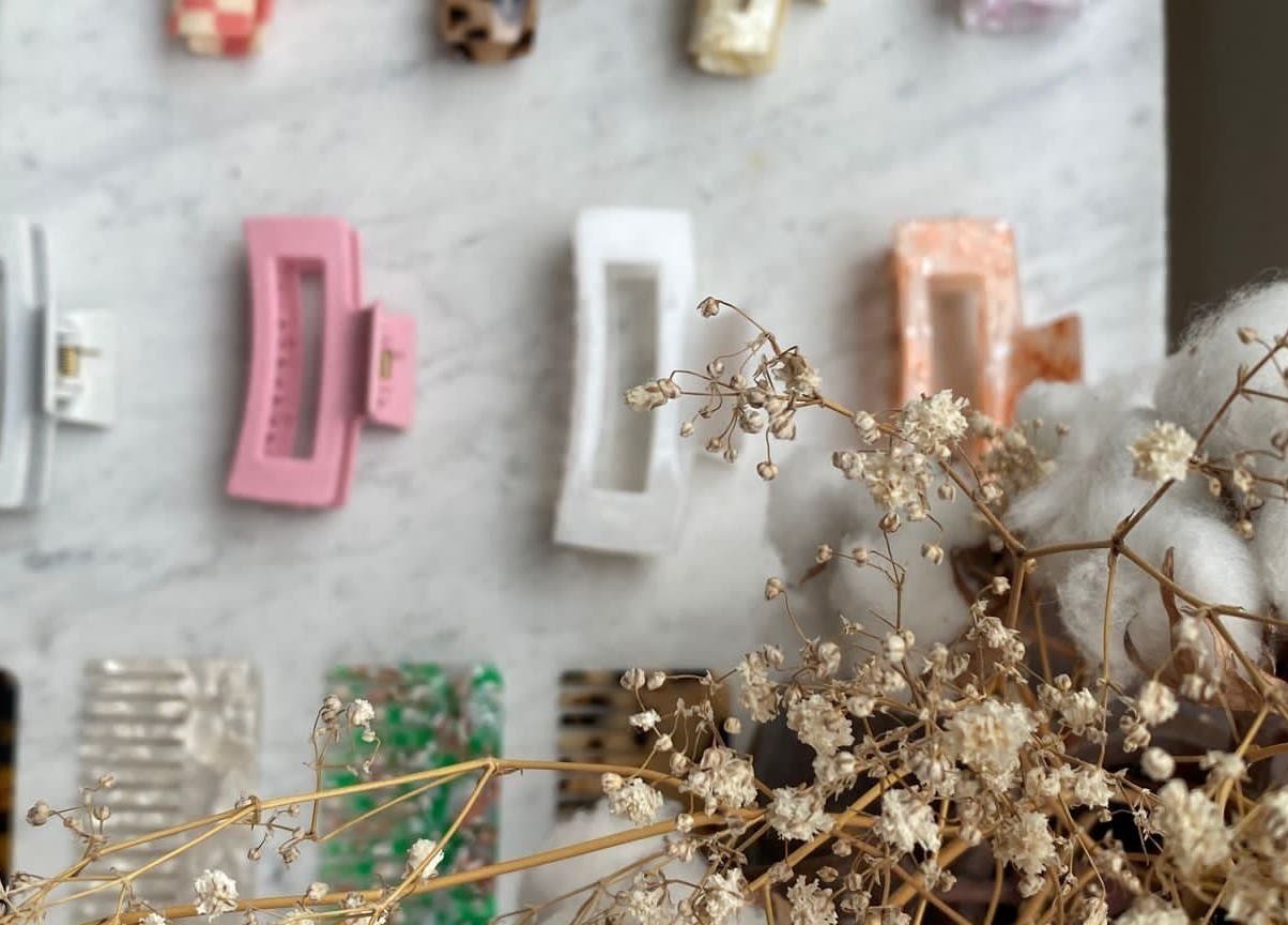 Assorted hair clips on marble at Morgelyn Studio, Penzance, England, GB with dried flowers.