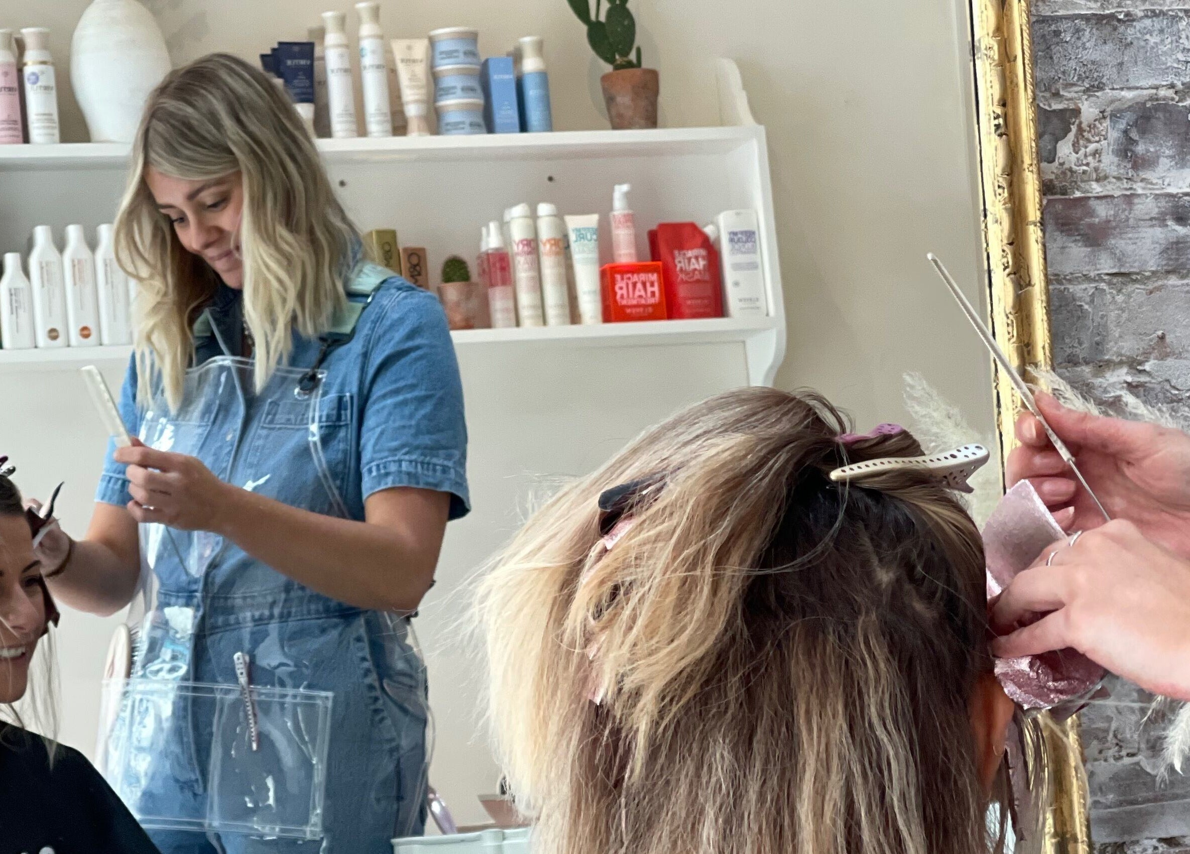 Hair stylist working on a client at Morgelyn Studio, Penzance, England, GB with products in the background.