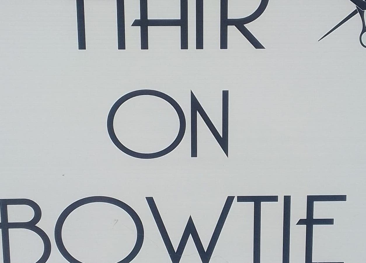 Sign for Hair on Bowtie, Plettenberg Bay, Western Cape, ZA, featuring stylish text and scissors icon.