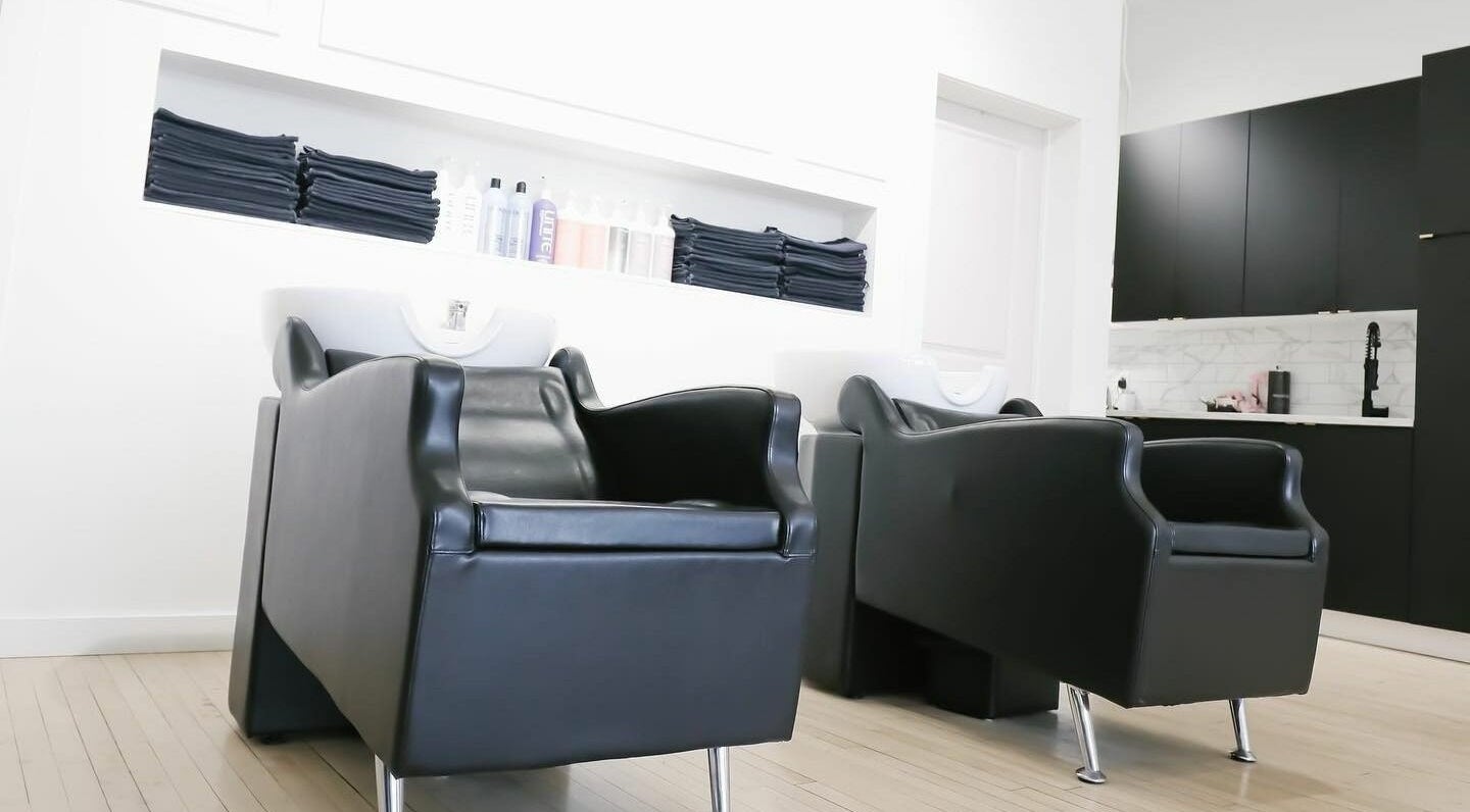 Elegant hair wash stations at Posh & Pixie, Kenora, Ontario, CA, showcasing sleek black leather chairs.