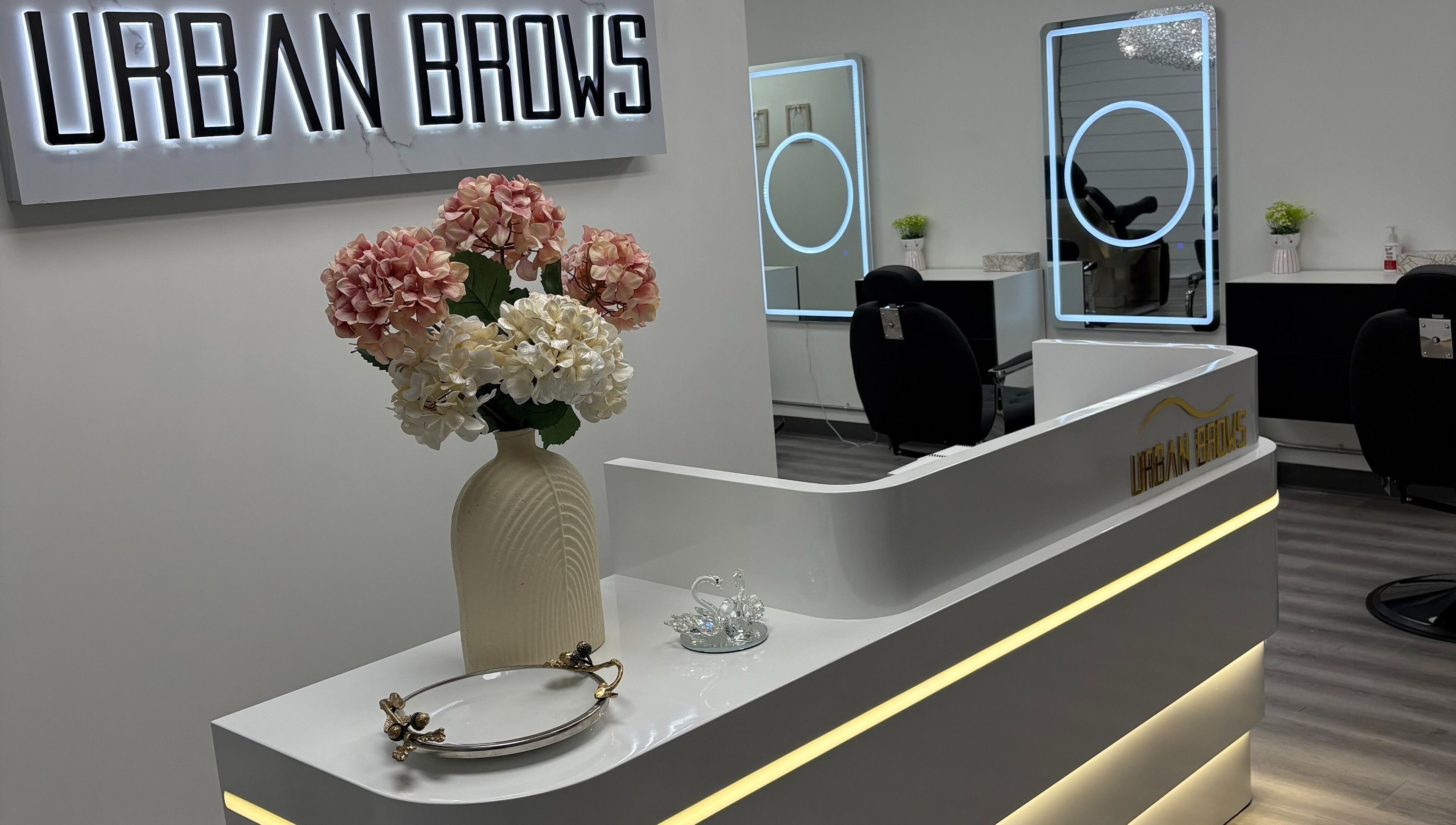 Reception area at Urban Brows West, Edmonton, Alberta, CA. Features sleek design with flower vase.