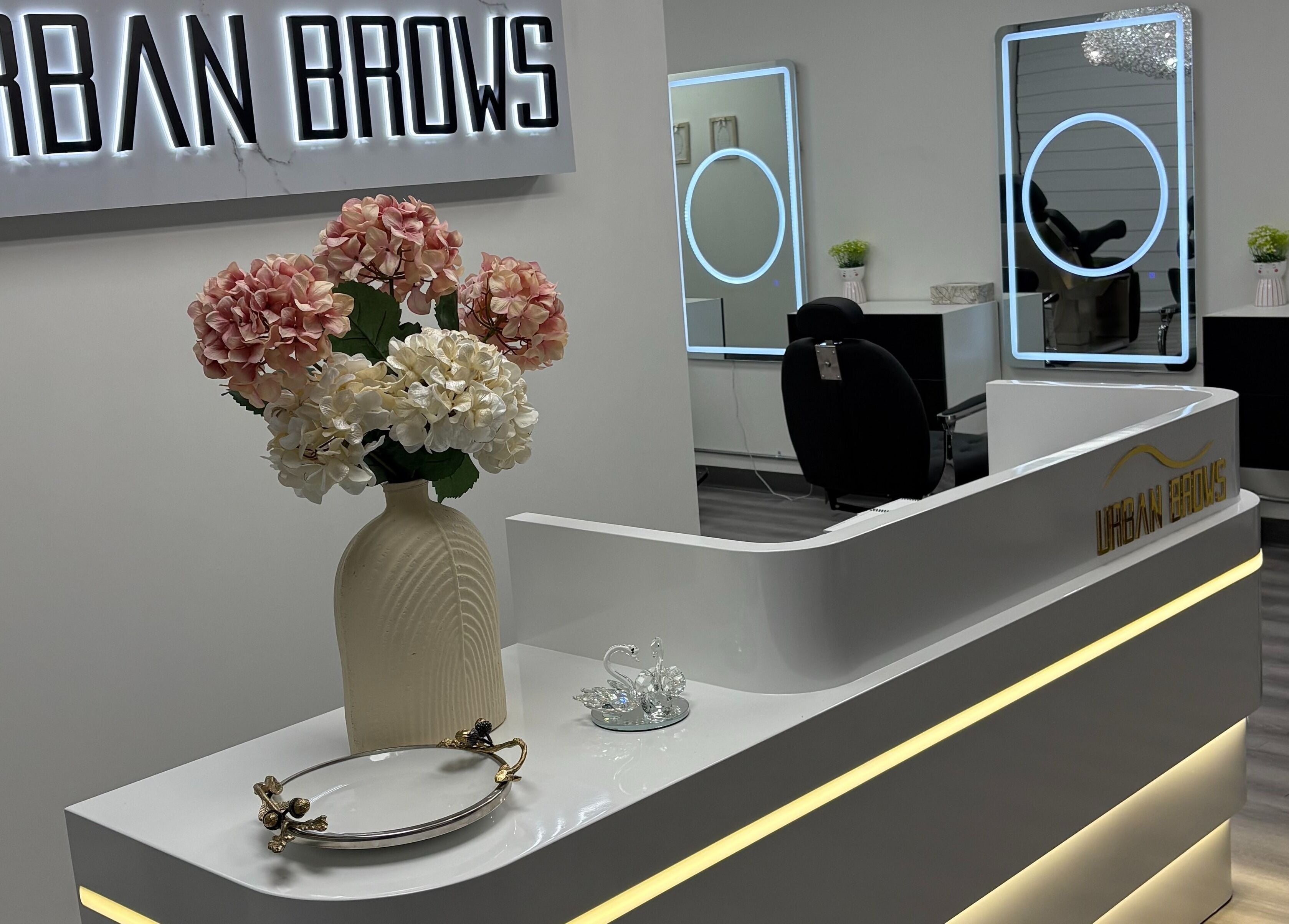 Reception area at Urban Brows West, Edmonton, Alberta, CA. Features sleek design with flower vase.