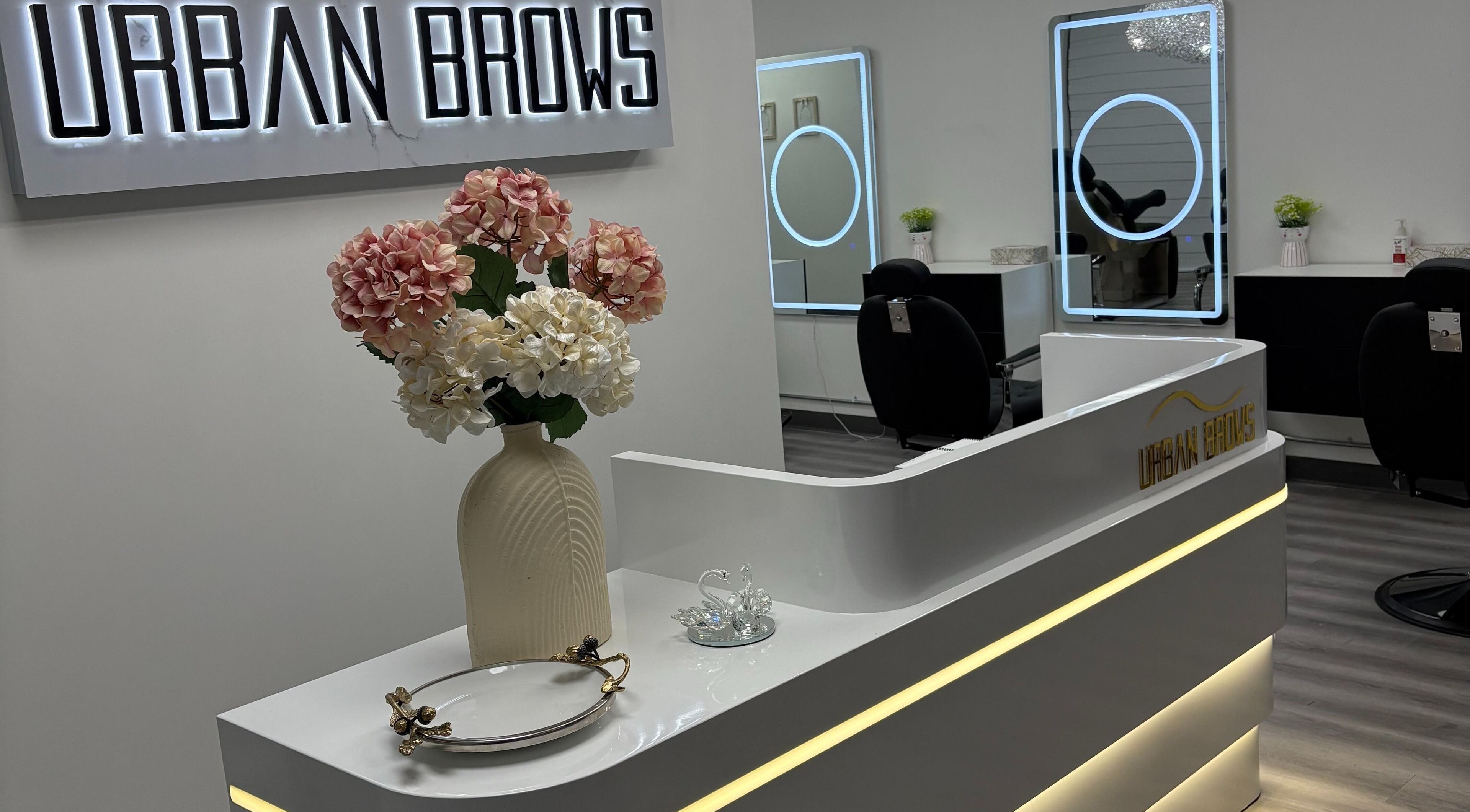 Reception area at Urban Brows West, Edmonton, Alberta, CA. Features sleek design with flower vase.