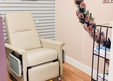 Relaxing beige chair in Premier Beauty, Berea, Kentucky, US, beside floral decor and treatment supplies.