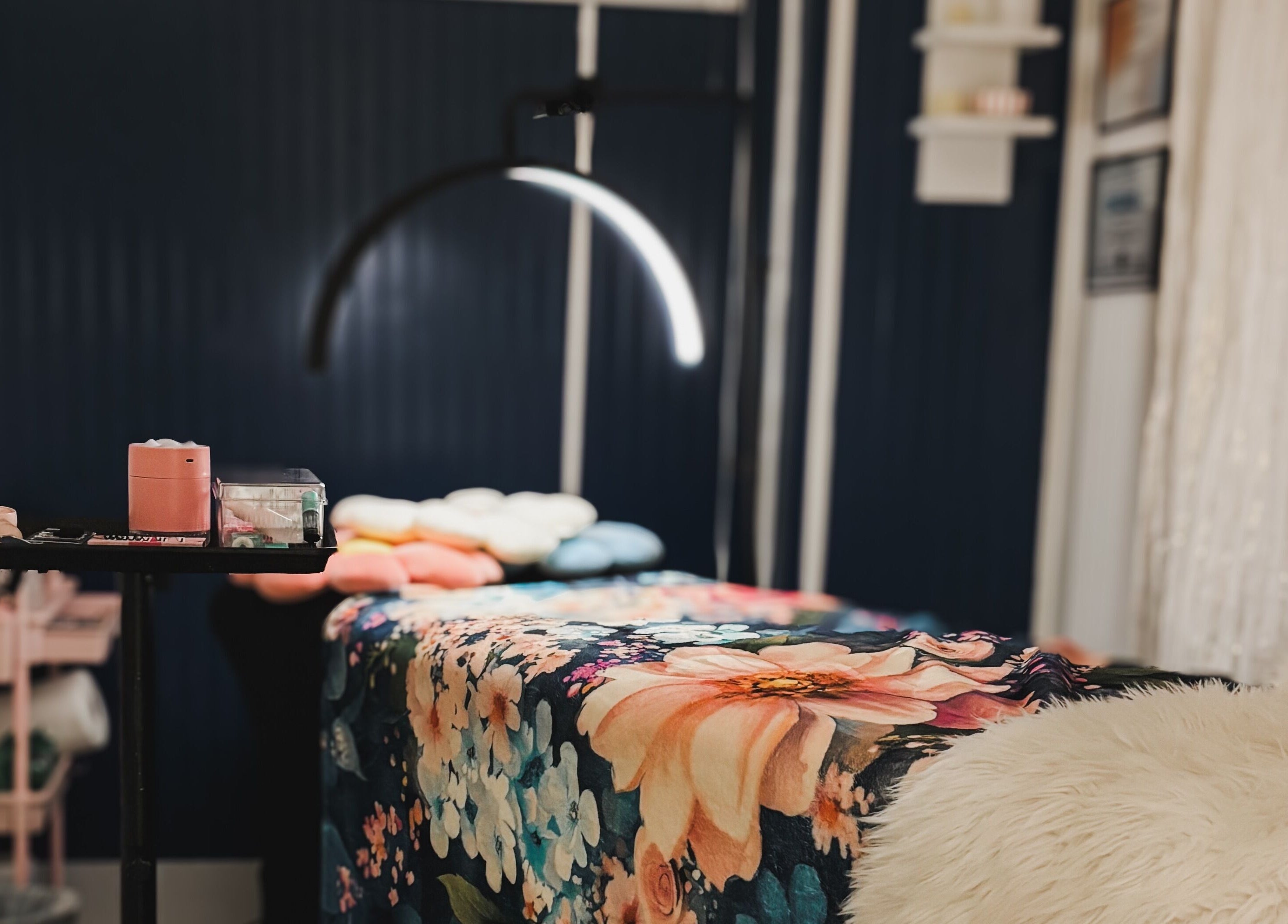 A cozy treatment room at Premier Beauty in Berea, Kentucky, US, featuring a floral bedspread and soft lighting.