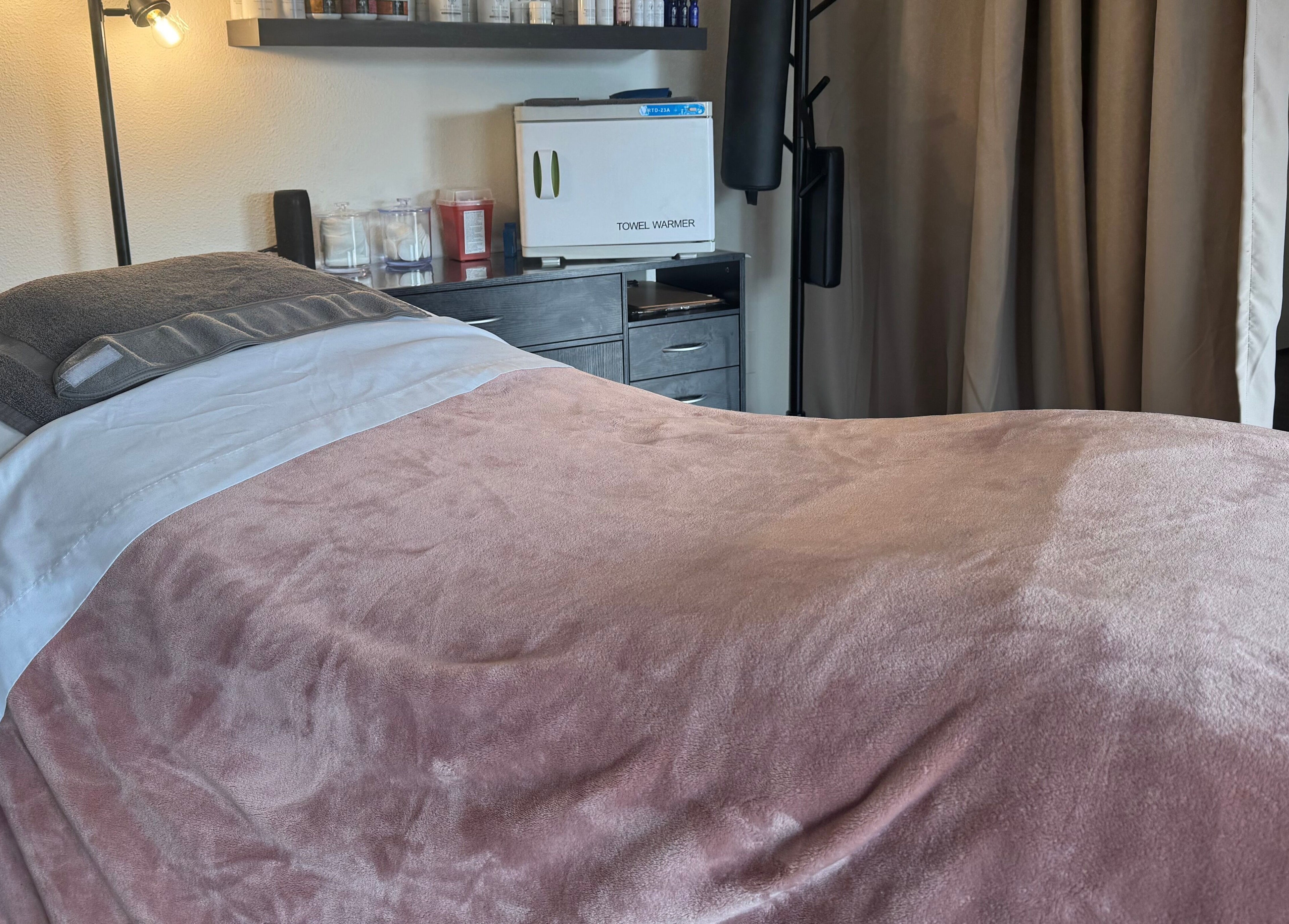 Cozy treatment room at Skinfluential LLC, West Linn, Oregon, US, with plush pink blanket and modern decor.