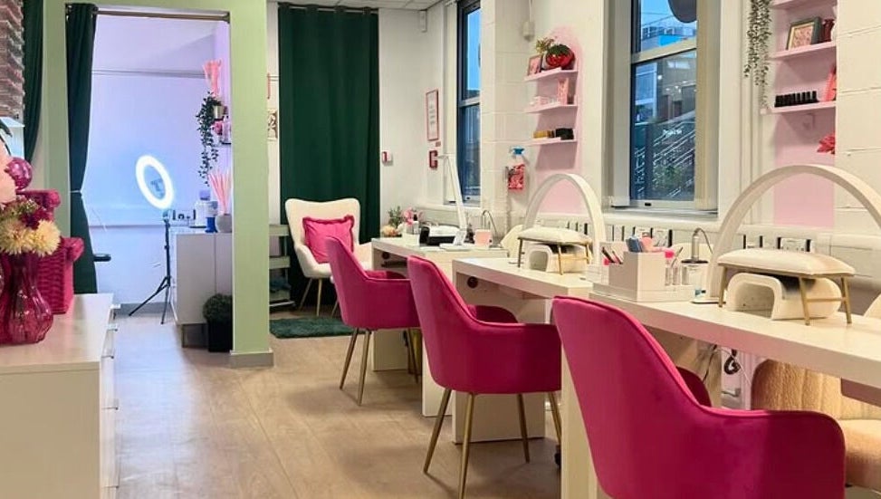 Stylish interior of The Beauty Bar Bristol, Stoke Gifford, England, GB with pink chairs and a nail station.