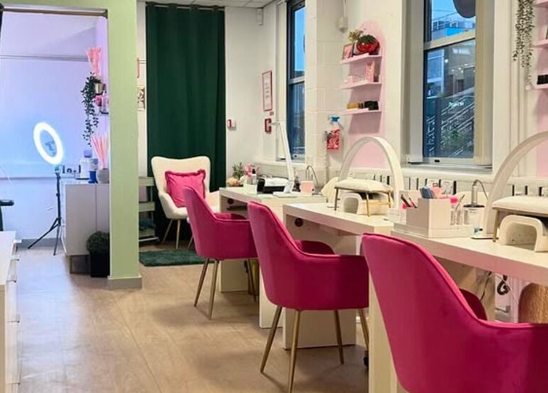 Stylish interior of The Beauty Bar Bristol, Stoke Gifford, England, GB with pink chairs and a nail station.