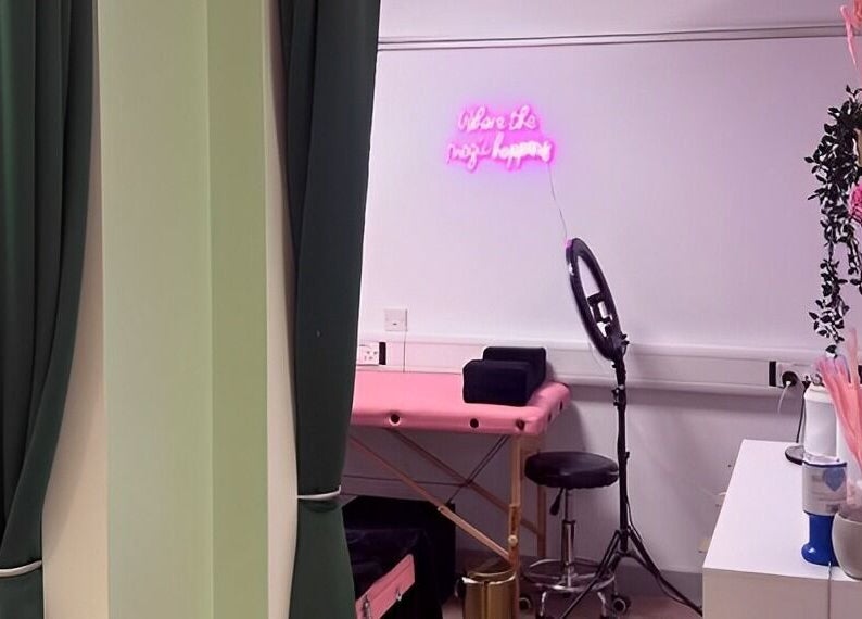 Cosy treatment room at The Beauty Bar Bristol, Stoke Gifford, England, GB, with pink table and neon sign.