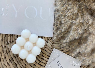 Delicate candle with cards at Bare Beauty, Bournemouth, England, GB, on a woven mat.